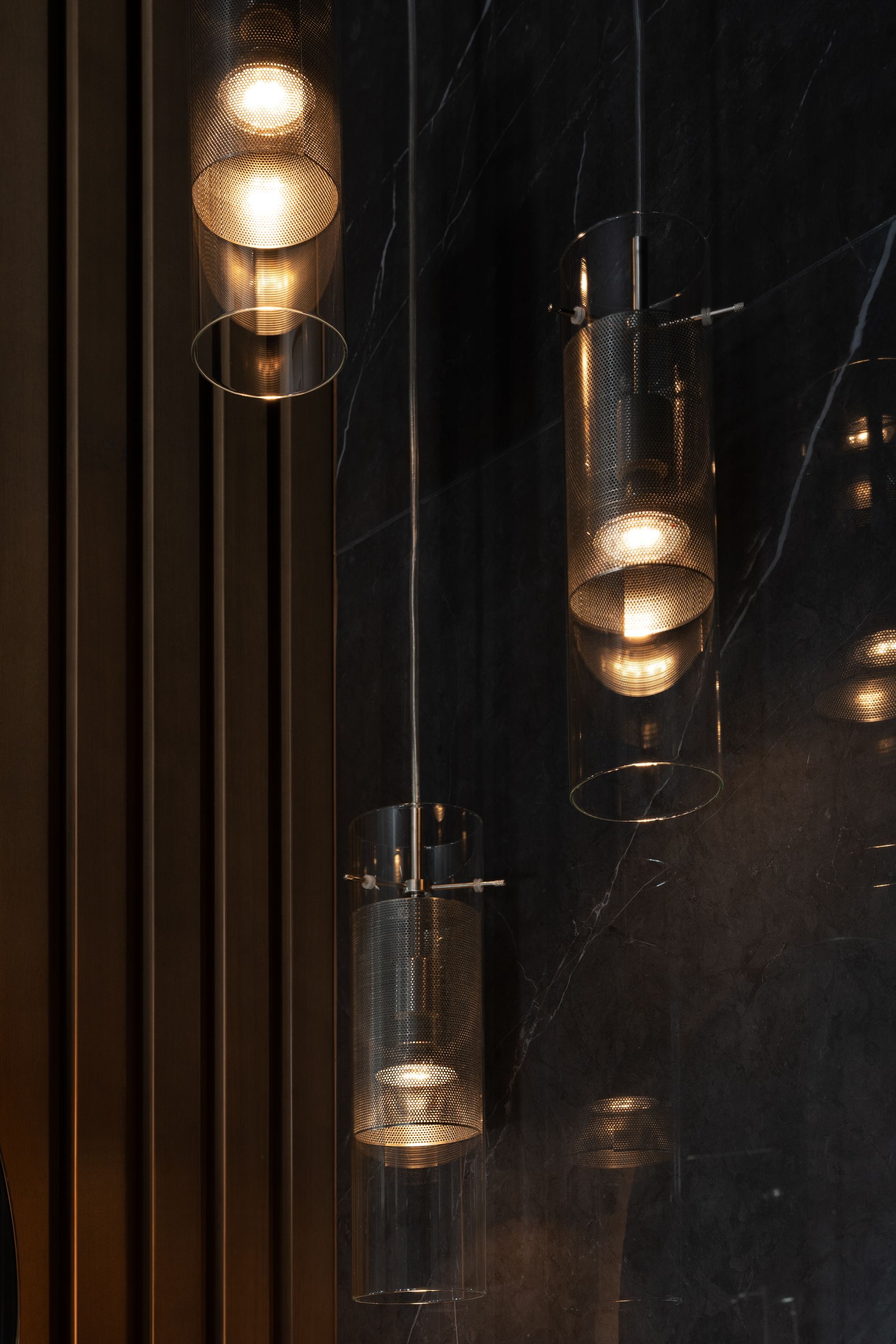 Three hanging pendant lights against a dark, textured wall.