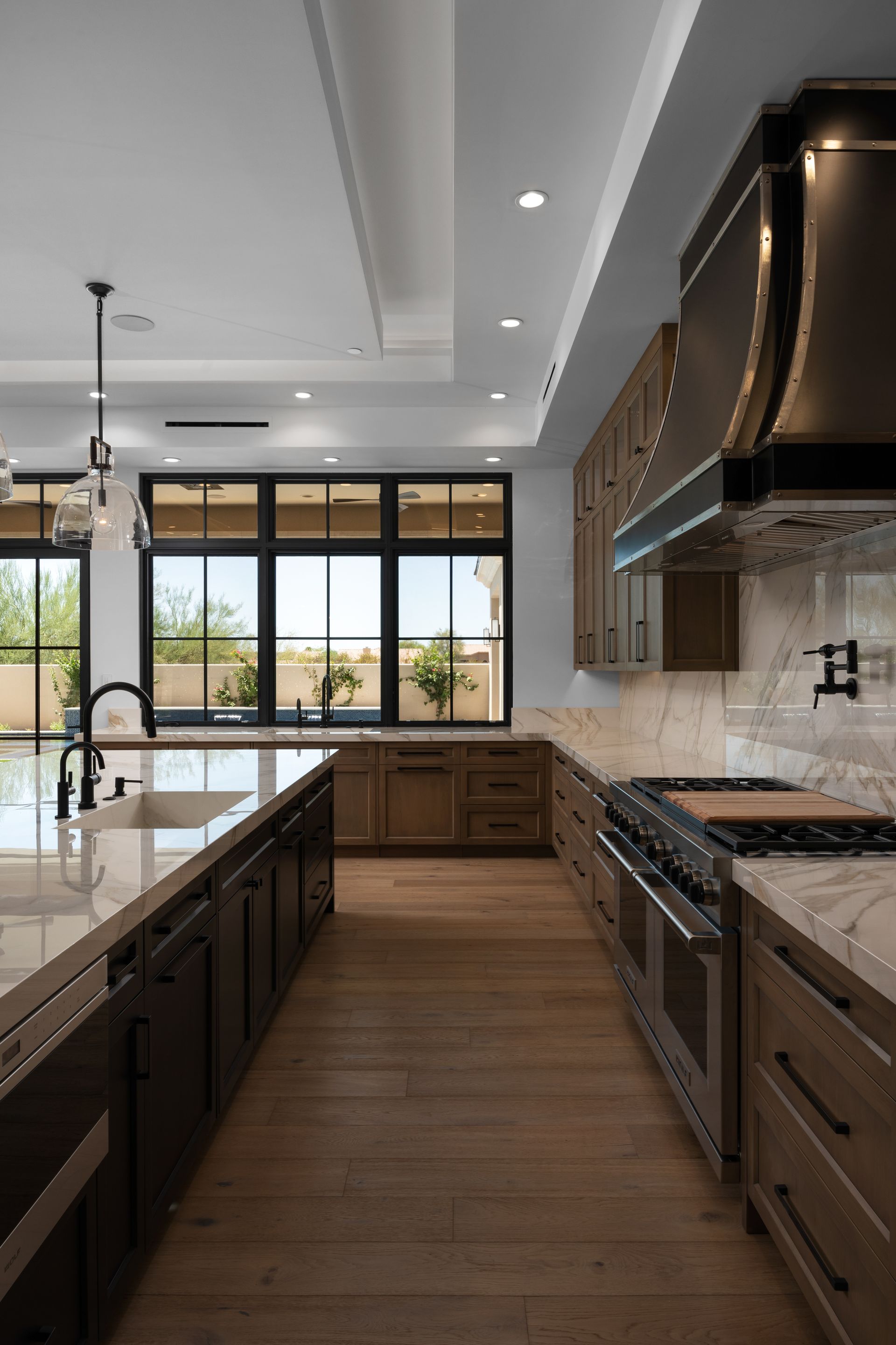 Modern kitchen with wood cabinets, island, and stainless steel appliances. Large window.