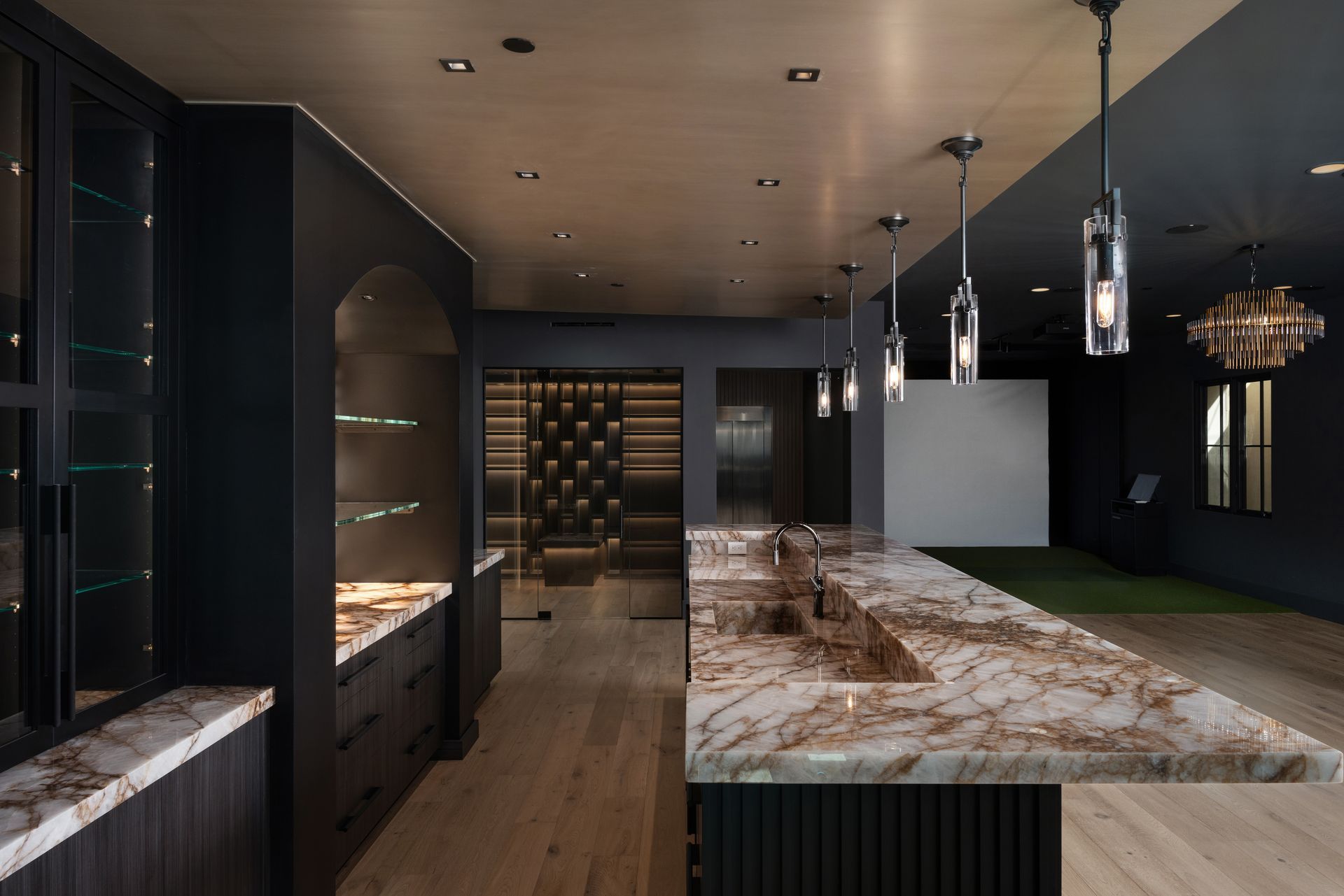 Modern kitchen with marble countertop, wood floor, dark cabinetry, and pendant lights.