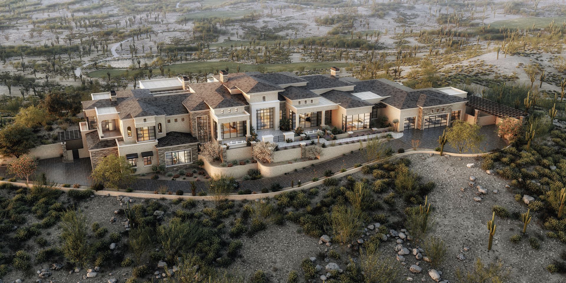Aerial view of a large, multi-sectioned house on a rocky, desert hillside. Beige walls, dark roof.