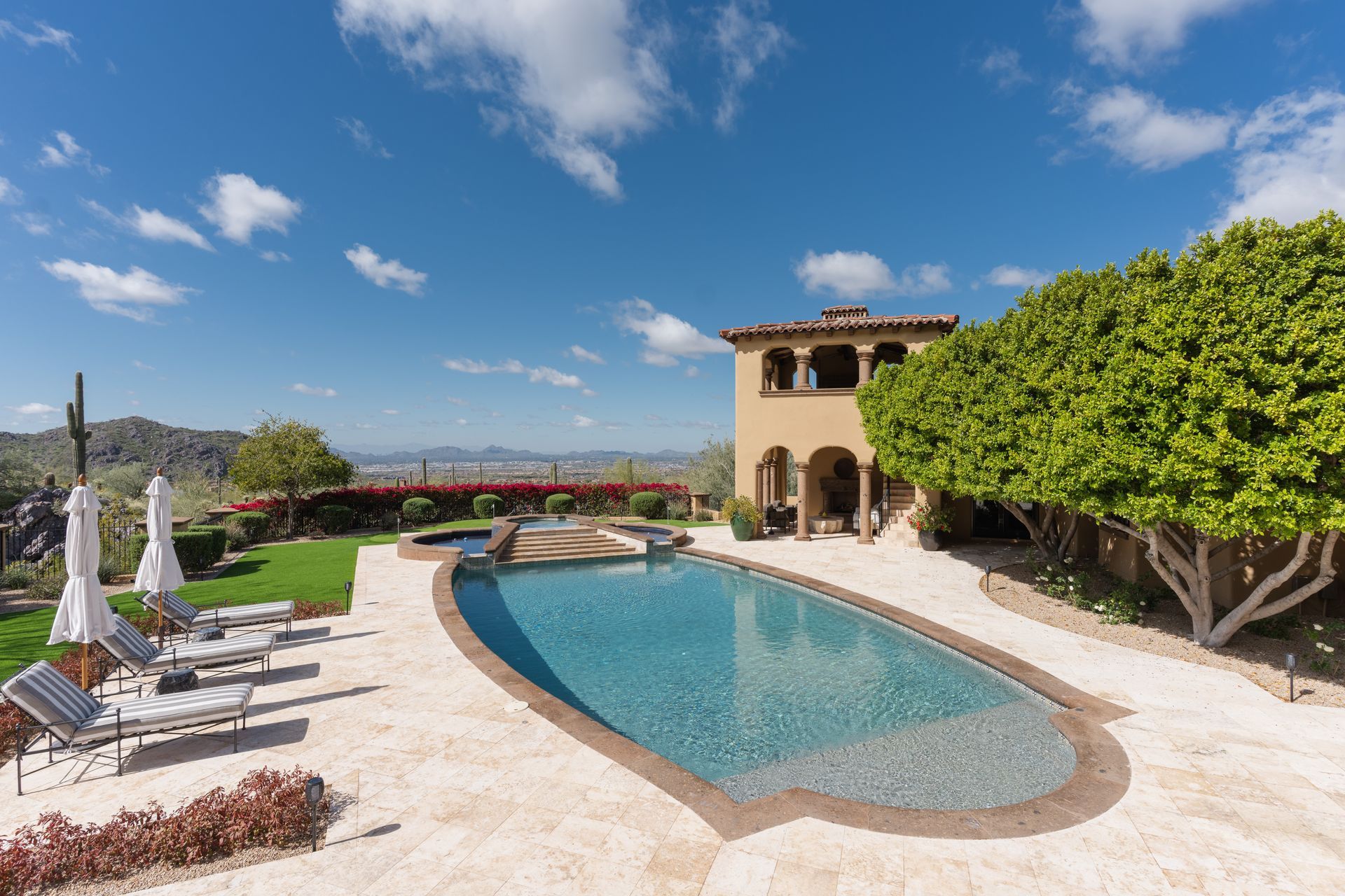 Luxury home with pool overlooking a city skyline on a sunny day.