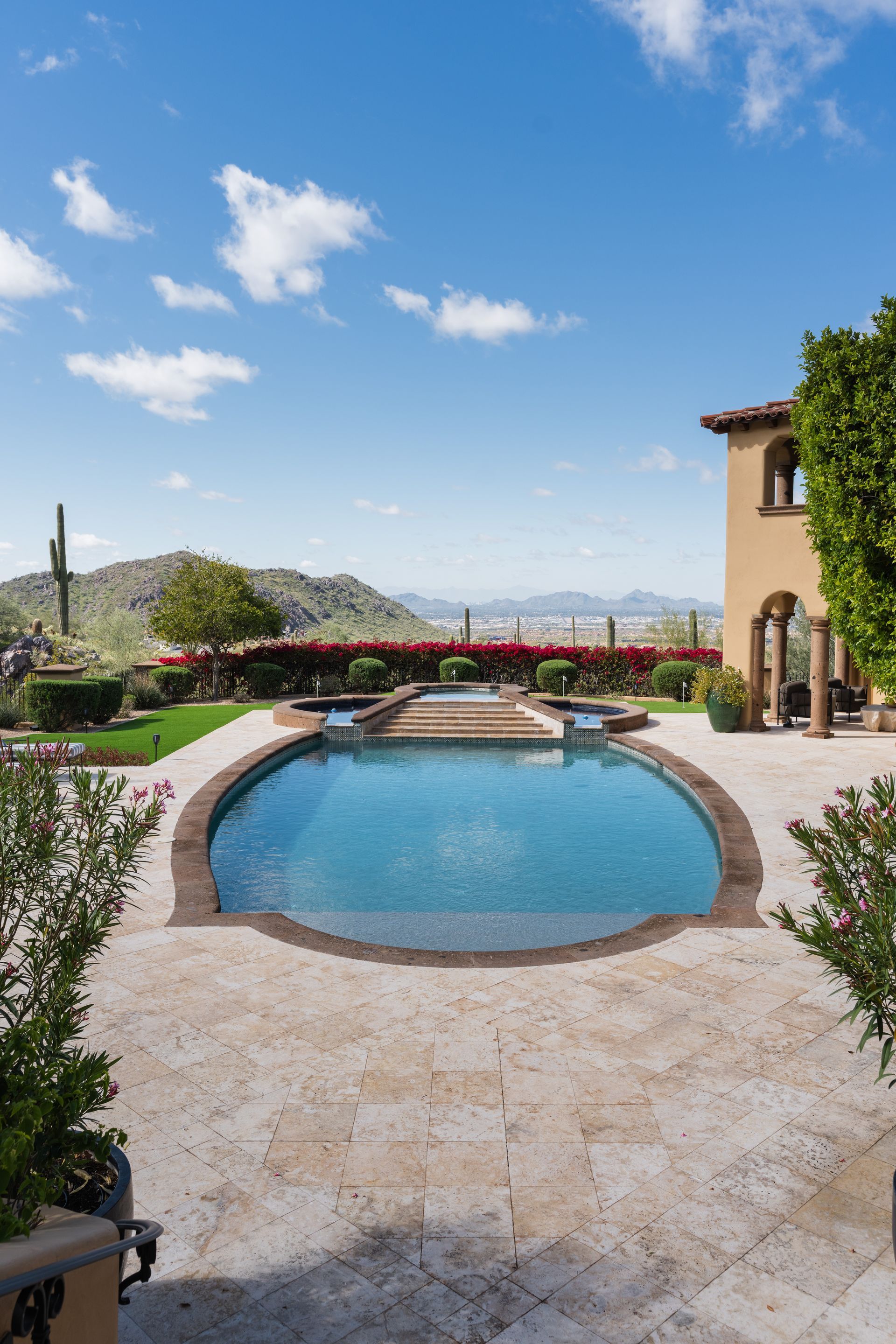 Swimming pool overlooking mountains under a bright blue sky.