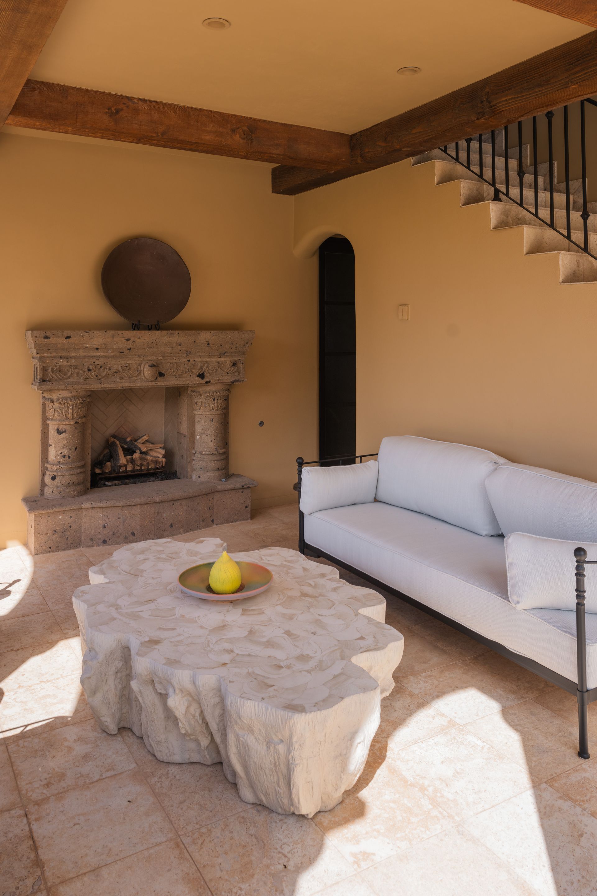 Outdoor seating area with fireplace, light sofa, and stone table.