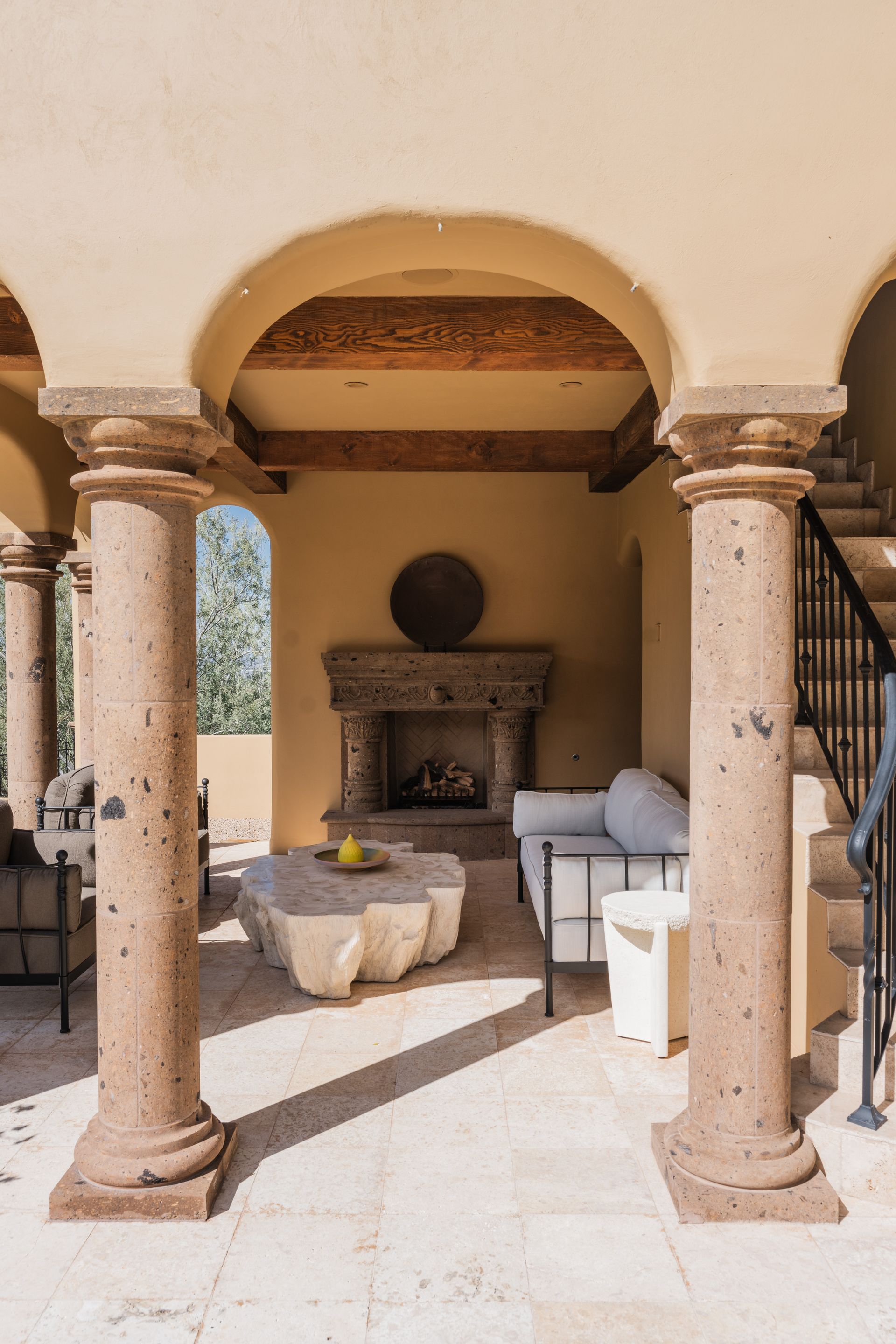 Outdoor patio with stone columns, fireplace, and seating.