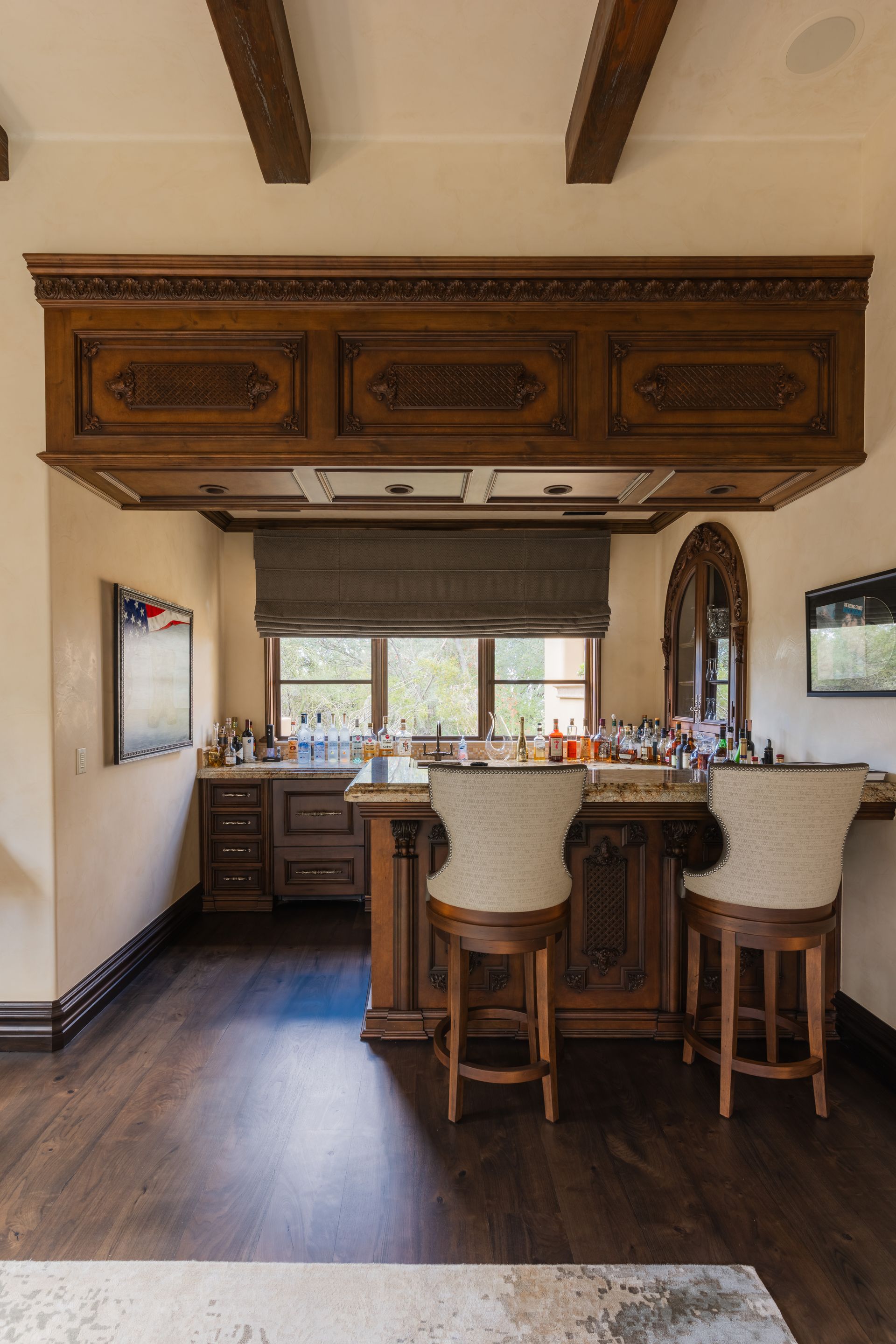 Elegant home bar with wooden accents, granite countertop, and two bar stools.