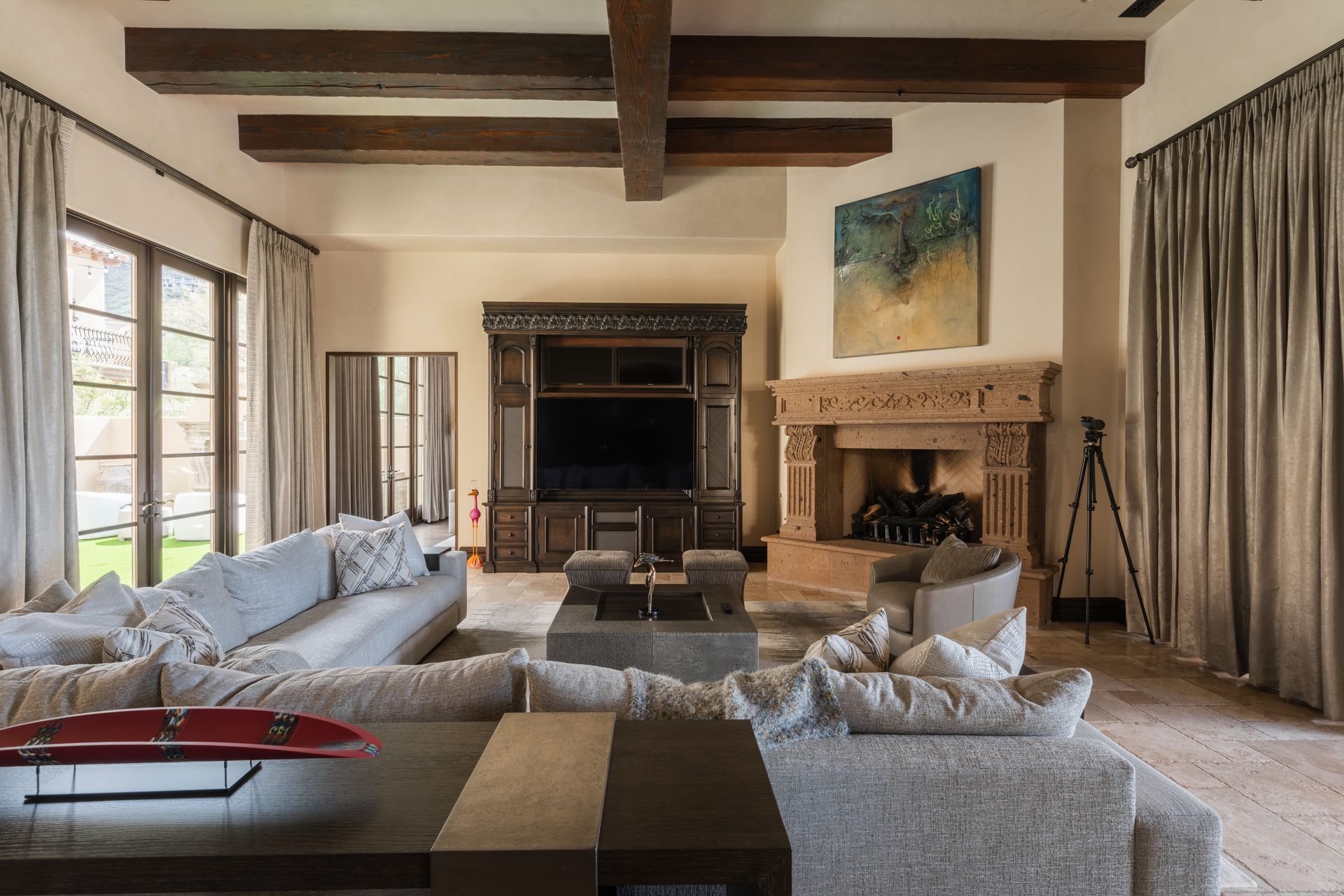 Luxurious living room with large sectional sofa, fireplace, and exposed beams.