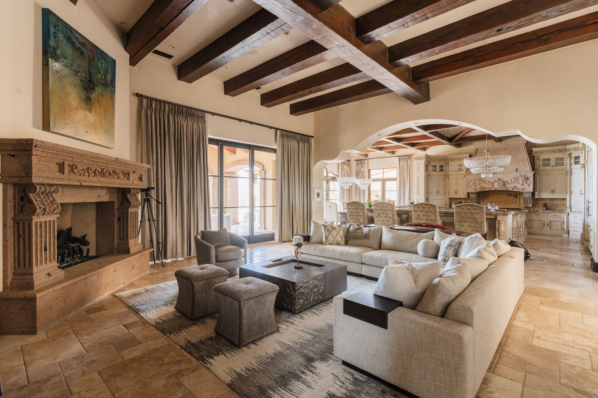 Spacious living room with stone fireplace, exposed wooden beams, and neutral-toned furniture.