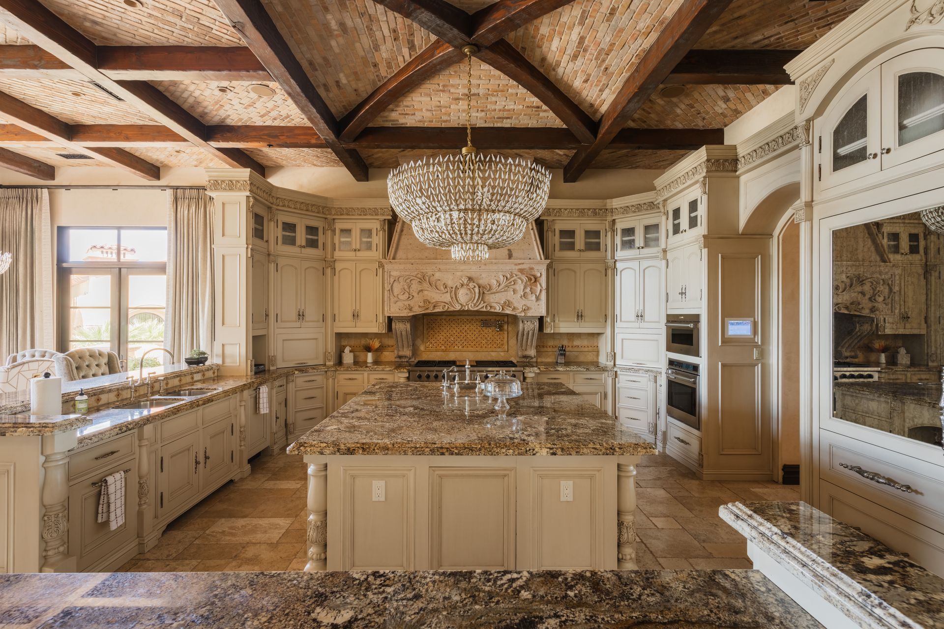 Elegant kitchen with cream cabinets, granite countertops, and a large chandelier.