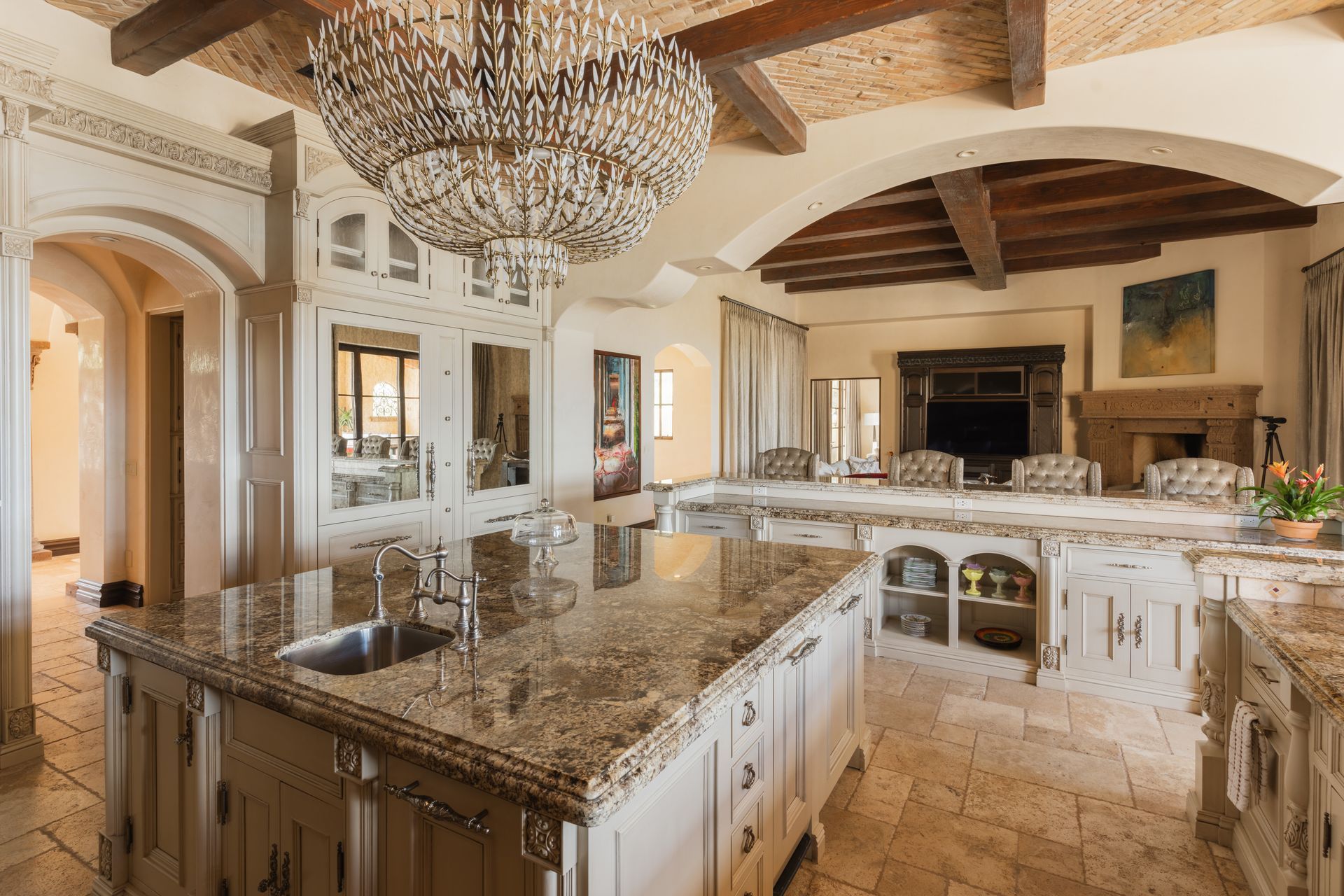 Elegant kitchen with large granite countertops, a chandelier, and wood-beam ceiling.