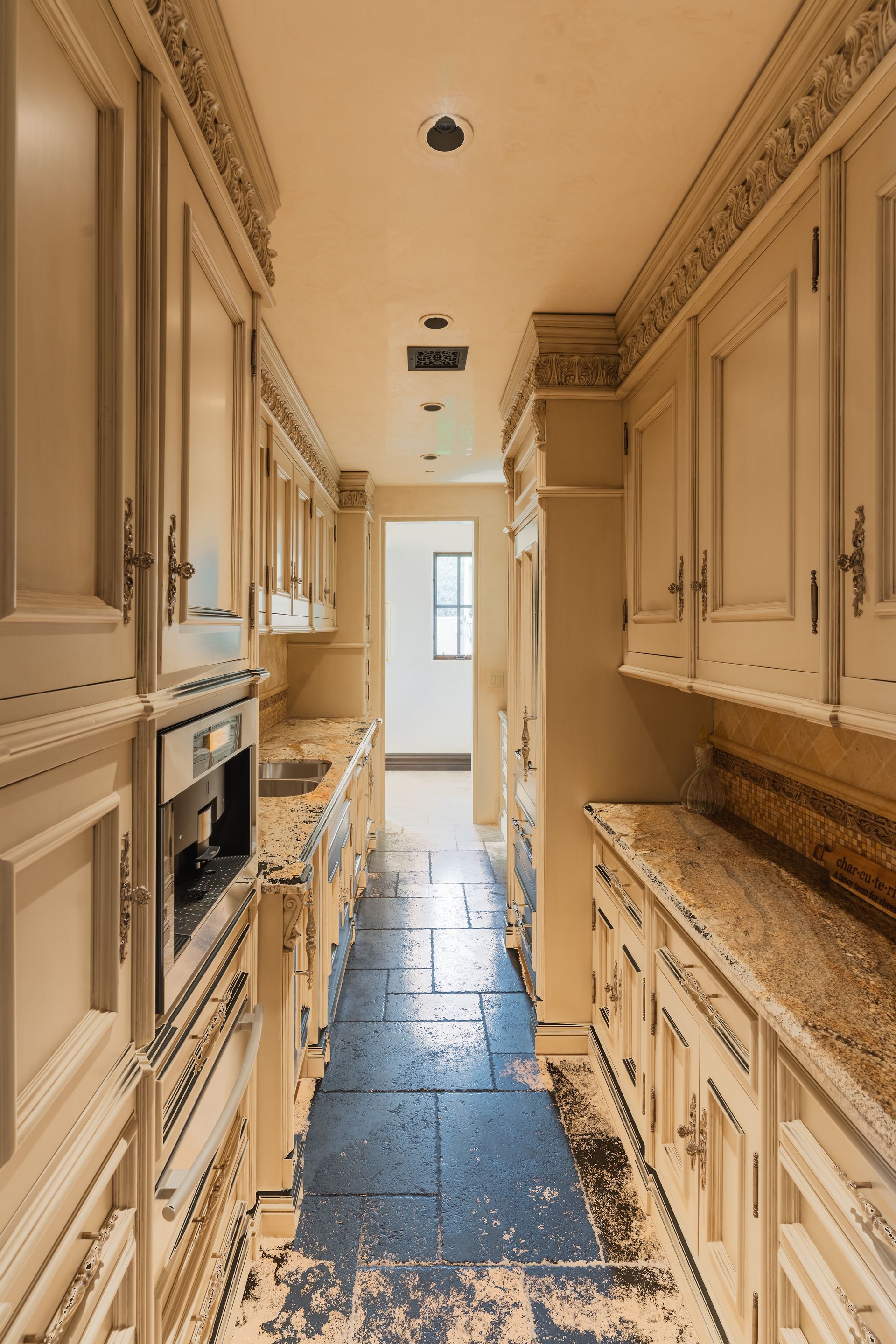 Narrow kitchen with cabinets on both sides and a dark floor.