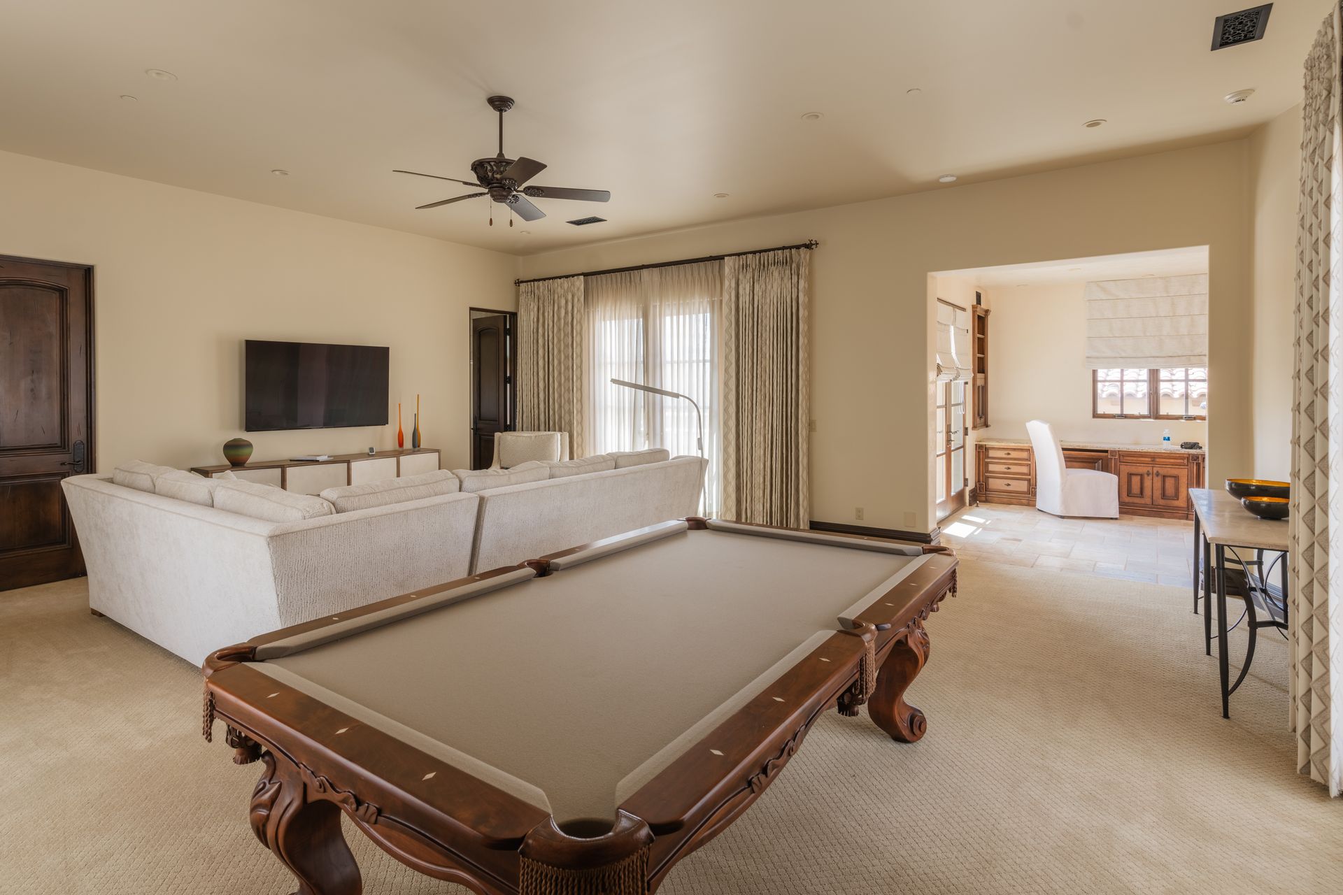 Spacious game room with pool table, large sectional sofa, and an adjoining office area.
