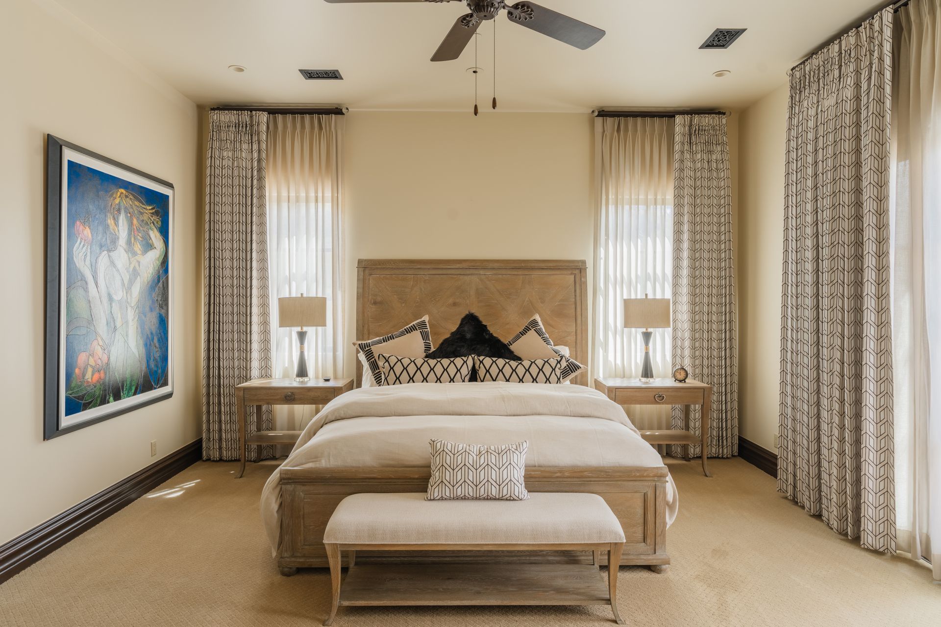 Bedroom with beige walls, a wooden bed, patterned curtains, and a painting.