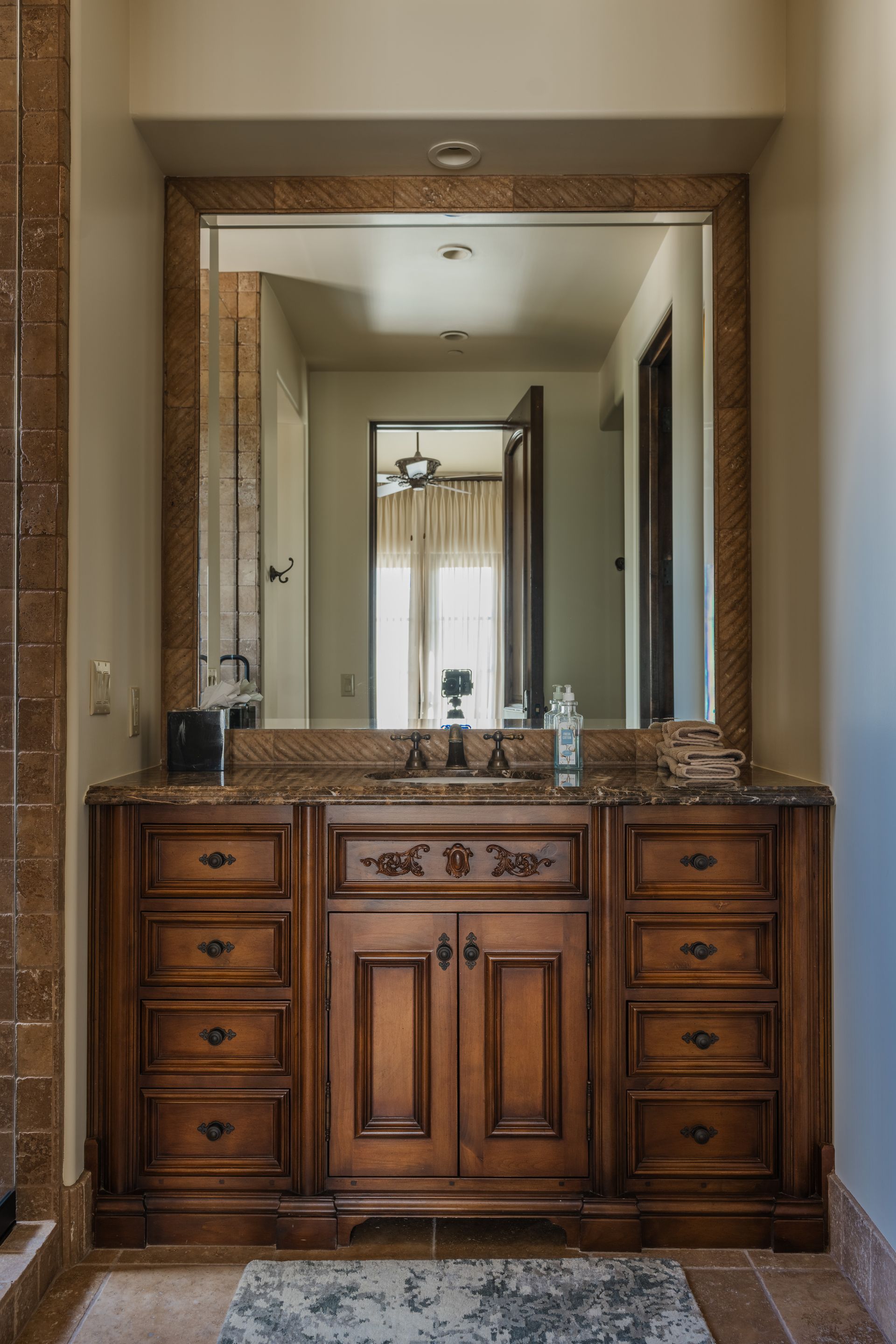 Wooden vanity with drawers and a large mirror in a bathroom.