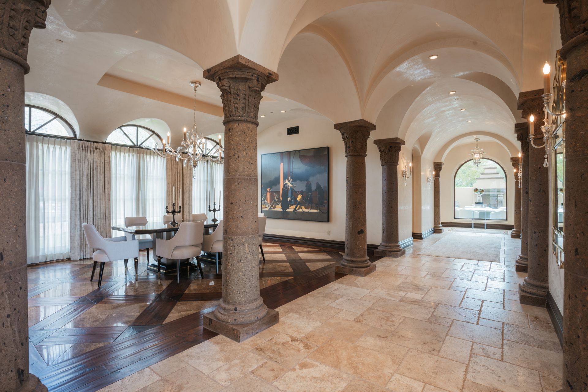Formal dining room with stone columns, arched ceiling, and marble flooring.