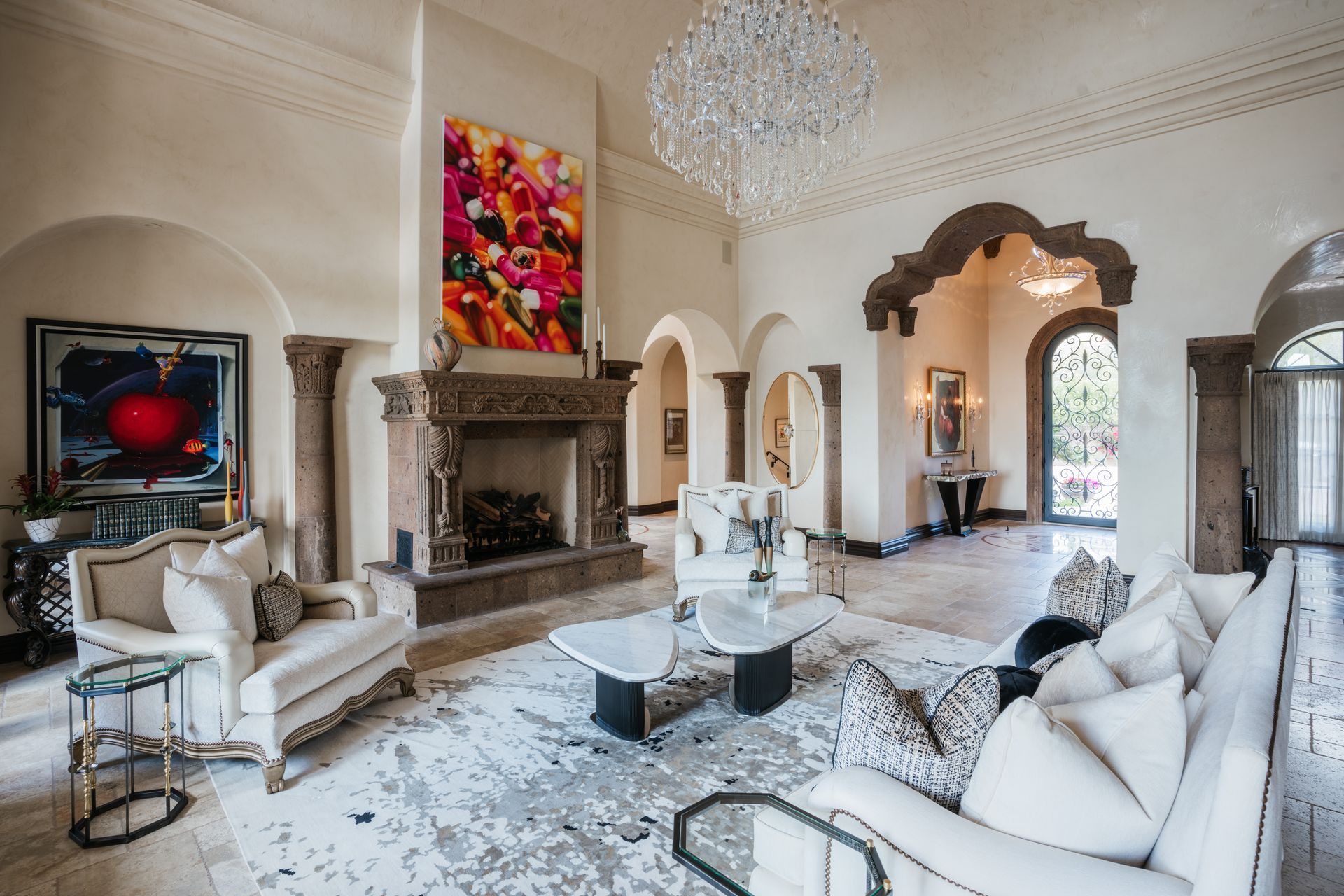 Luxurious living room with fireplace, art, chandelier, and white furniture.