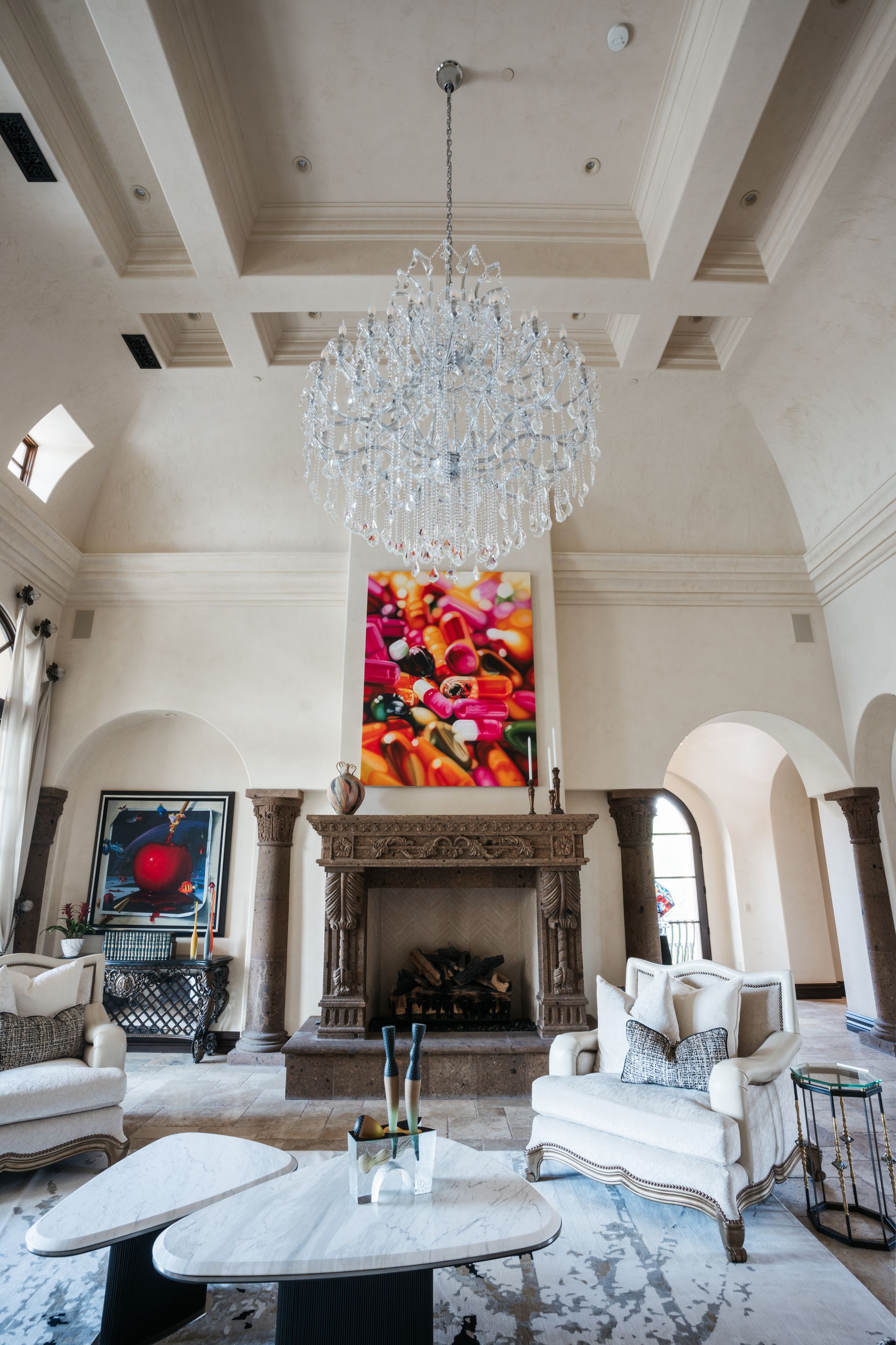 Luxurious living room with large chandelier, fireplace, and abstract art.