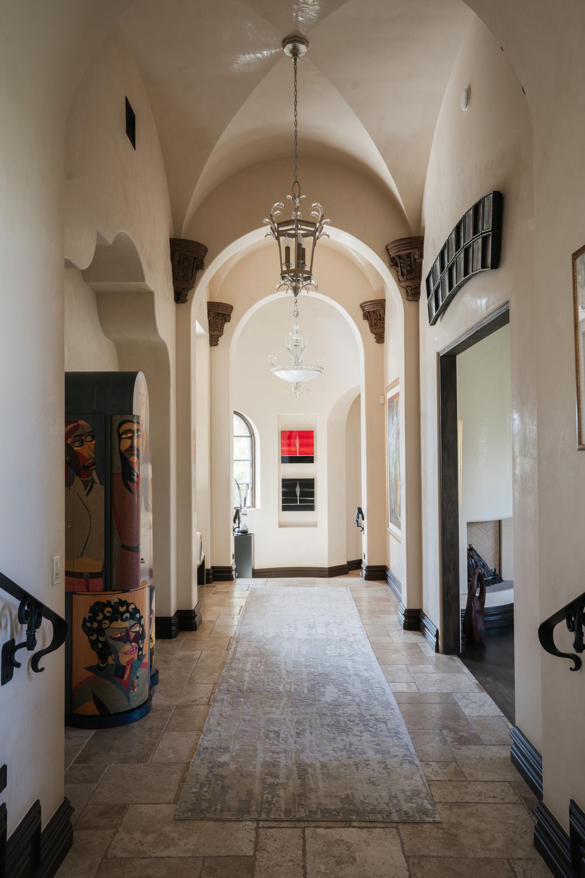 Long hallway with arched doorways, ornate light fixtures, and art on the walls.