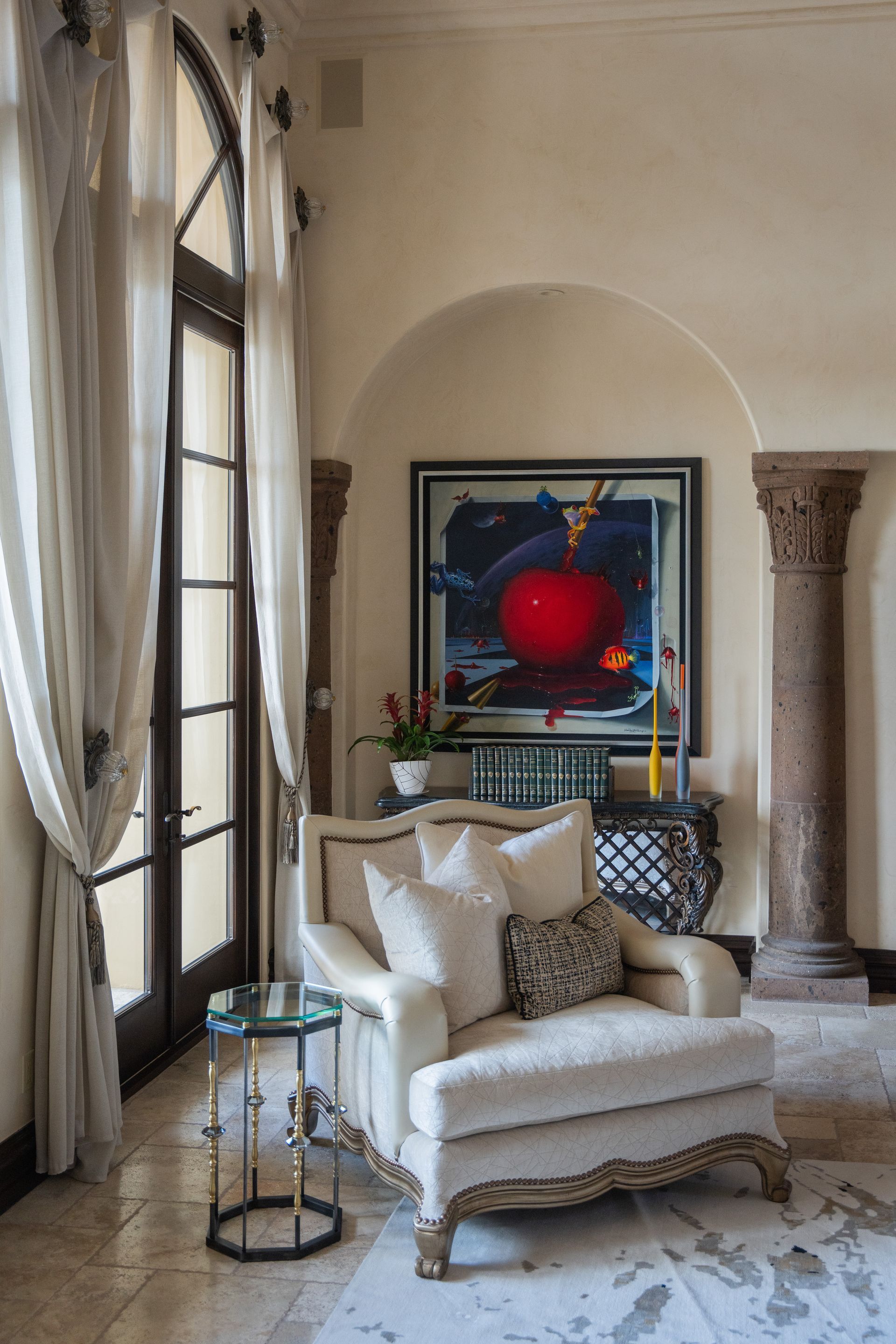 Cream-colored armchair by window with art and side table in a light-colored room.