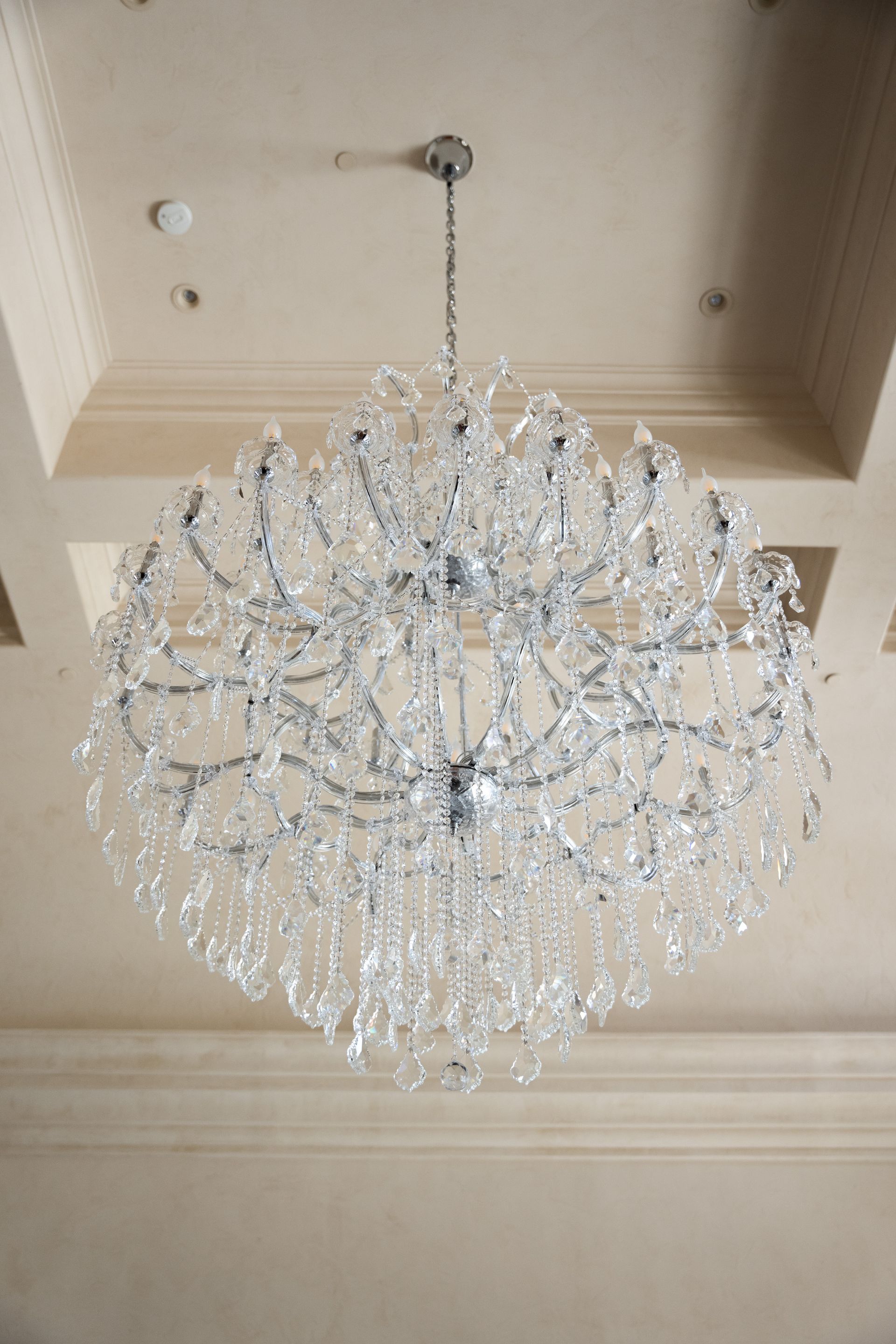 Crystal chandelier hanging from a beige ceiling.