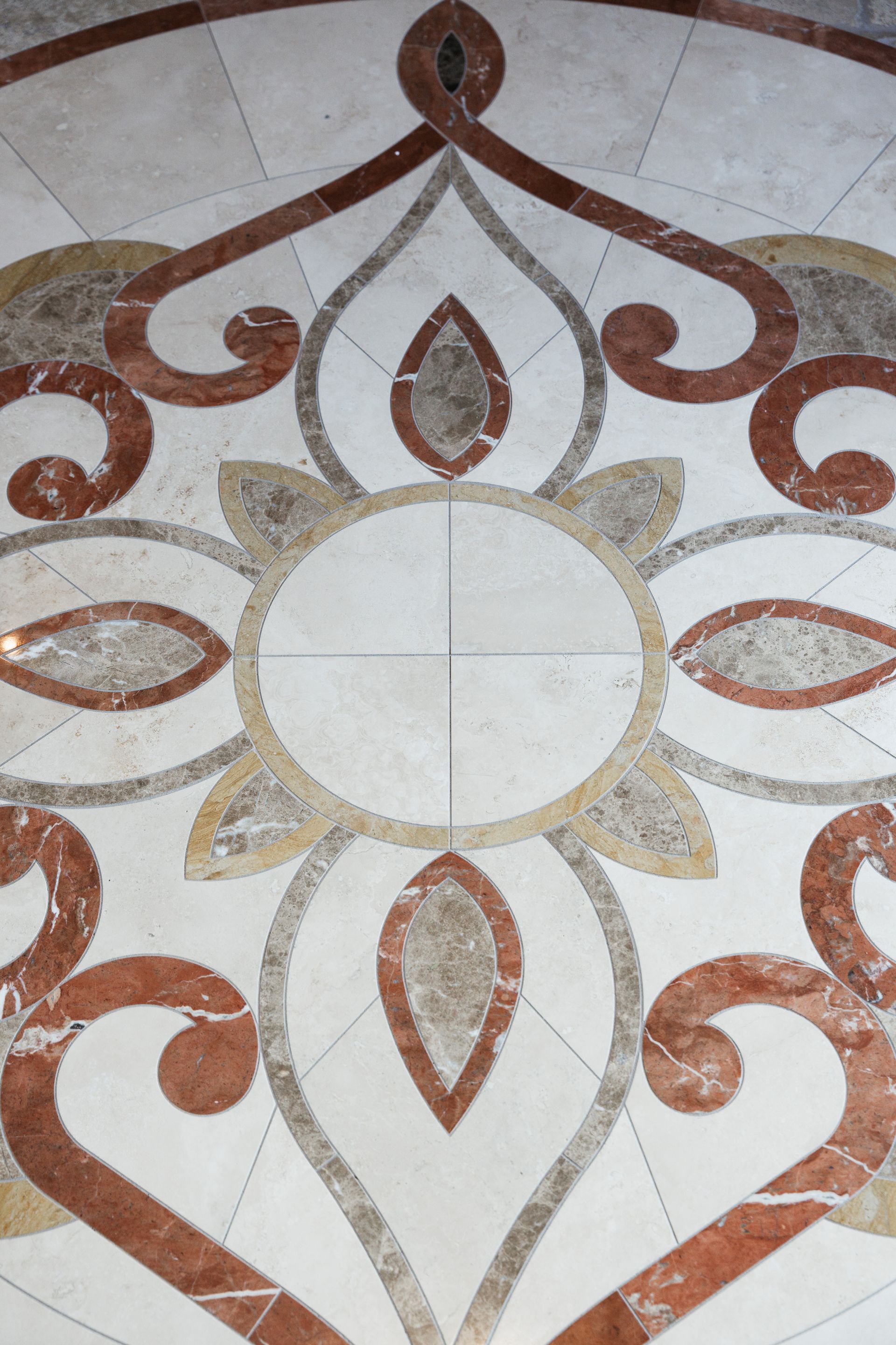 Ornate floor tile design: red, gray, and gold floral pattern with a central circle and cross.