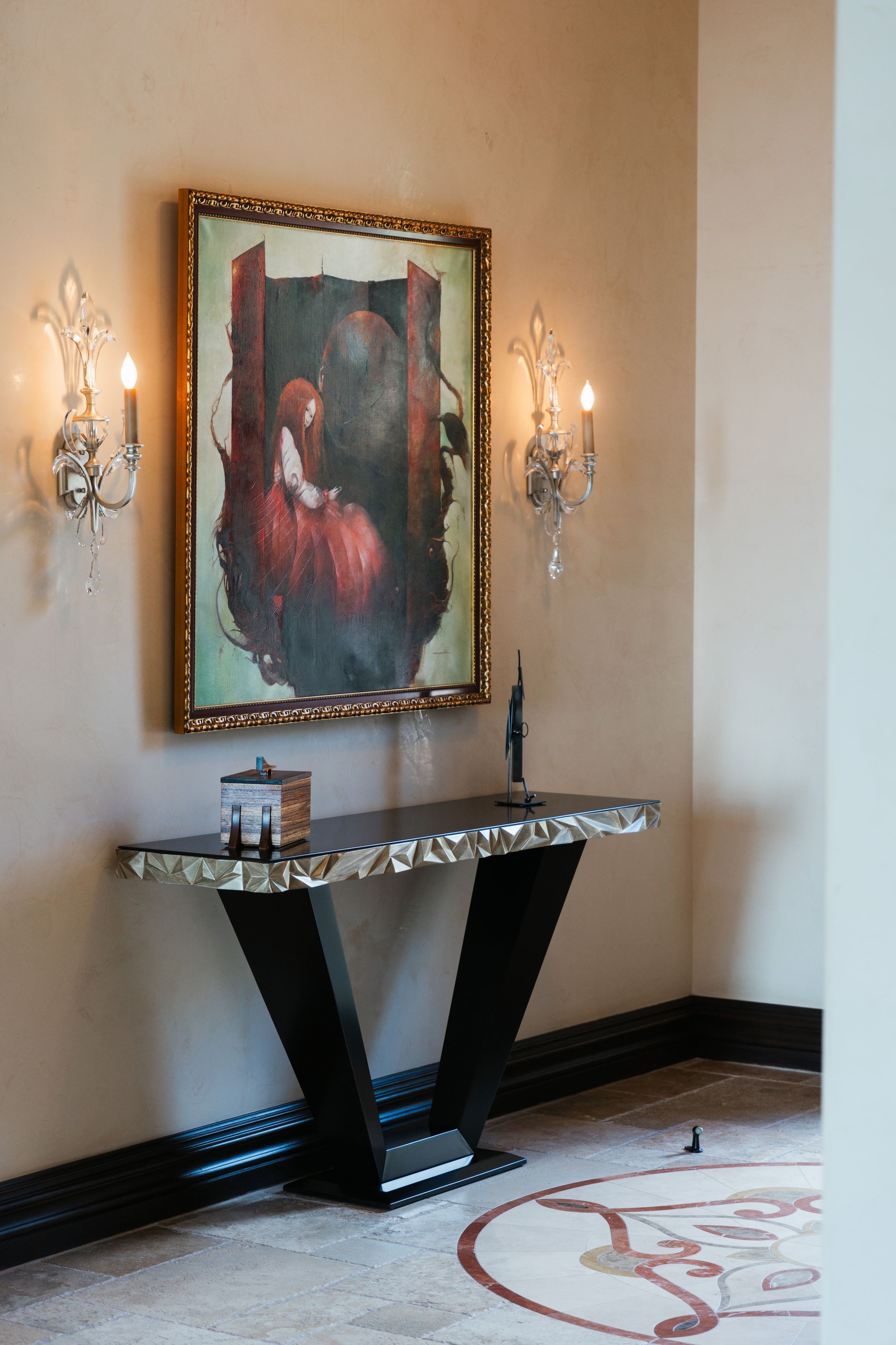 A console table with a painting and sconces on a wall, decorative interior.