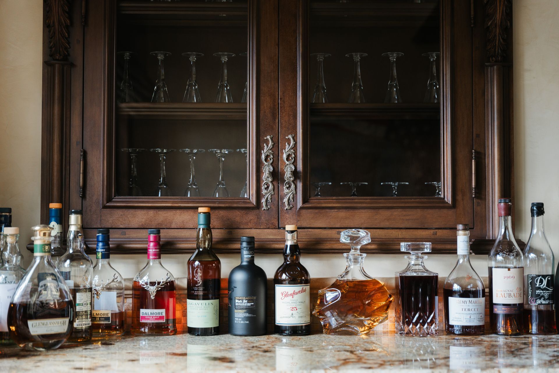 Bottles of liquor on a countertop, in front of a wood-paneled cabinet.