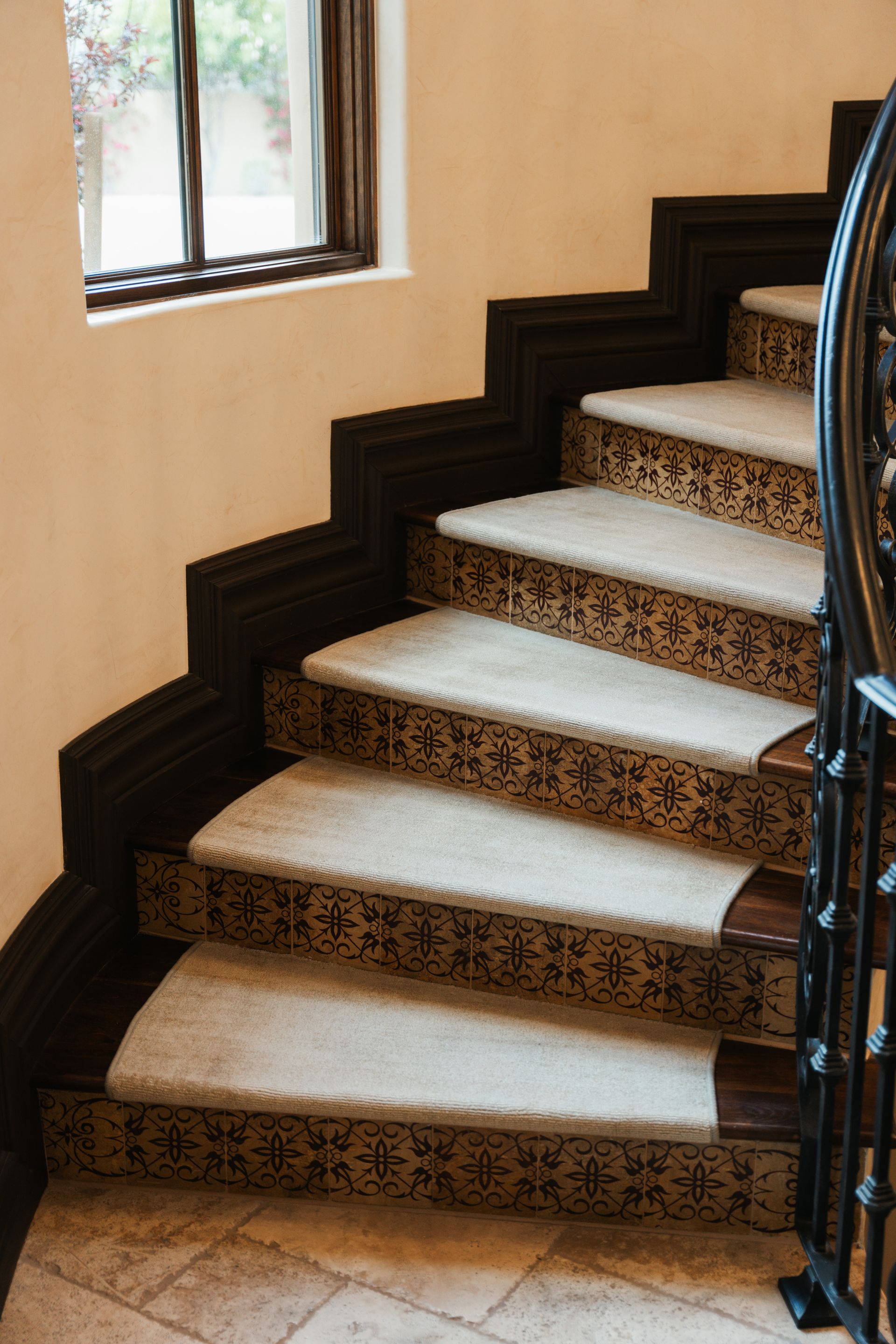 Curving staircase with tiled steps and dark wooden trim, near a window.