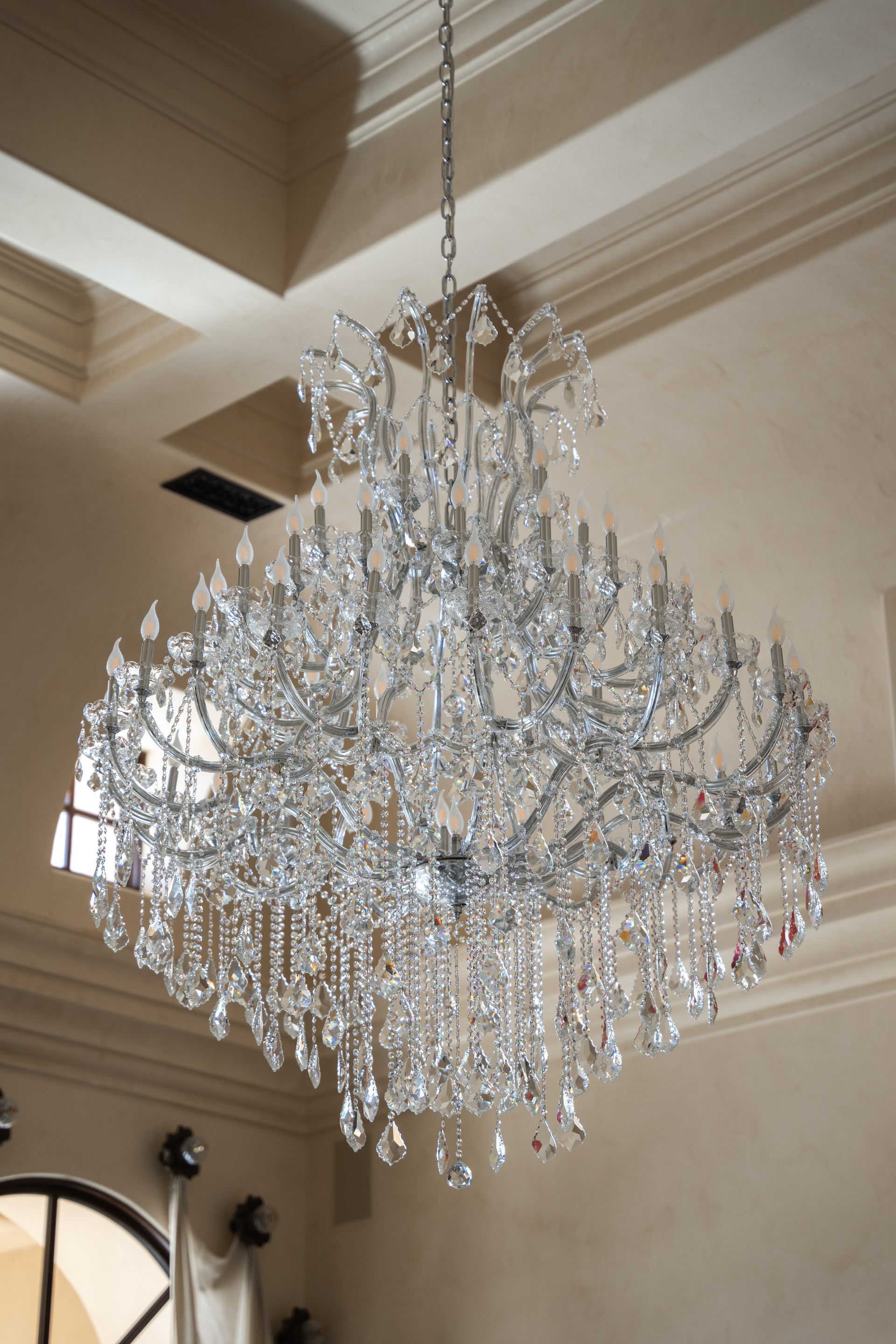 Large crystal chandelier hanging from a light-colored ceiling.