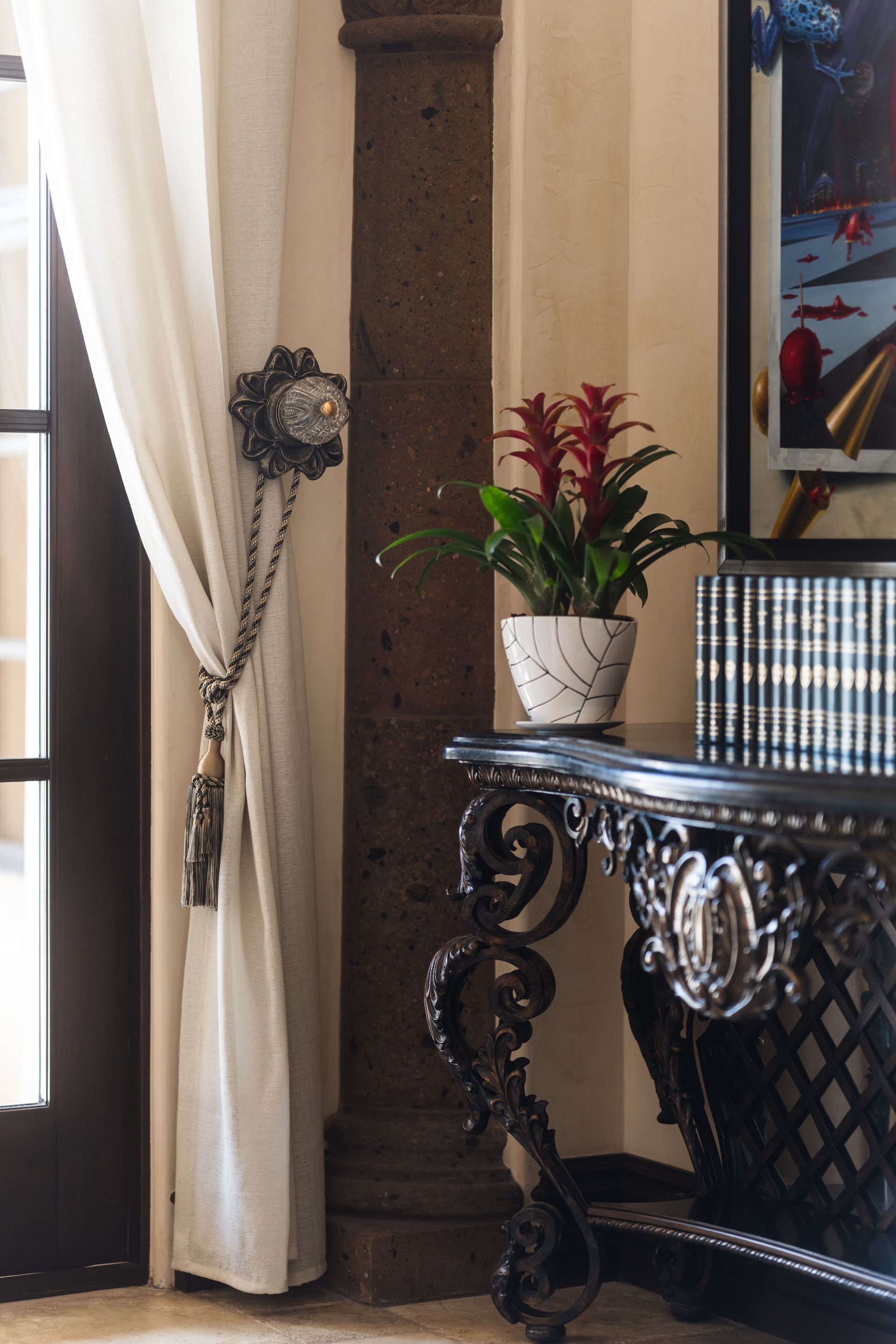 Elegant console table with floral arrangement, curtain, and ornate column.