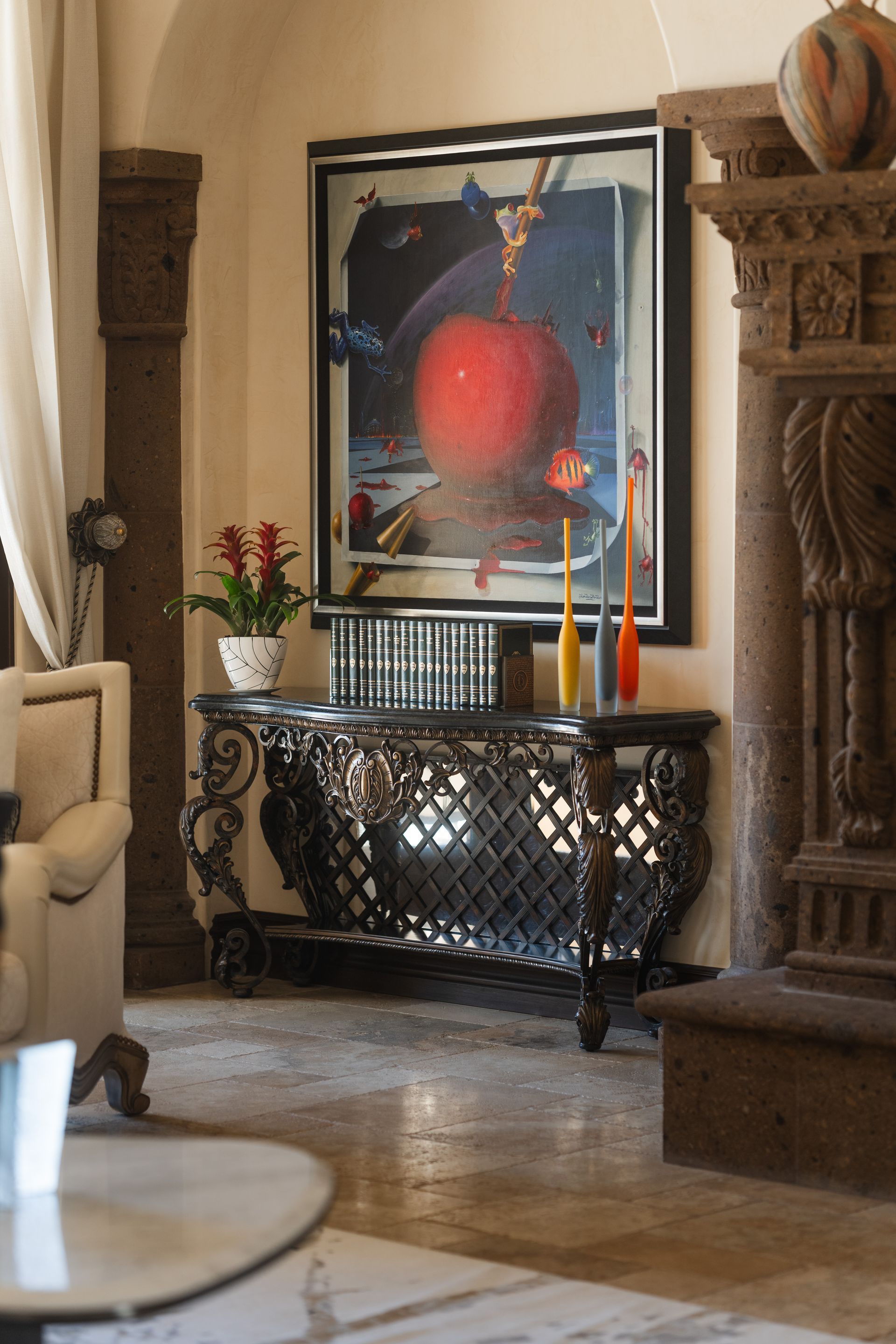 Ornate console table with art, plant, and tall candles, in a well-lit interior.