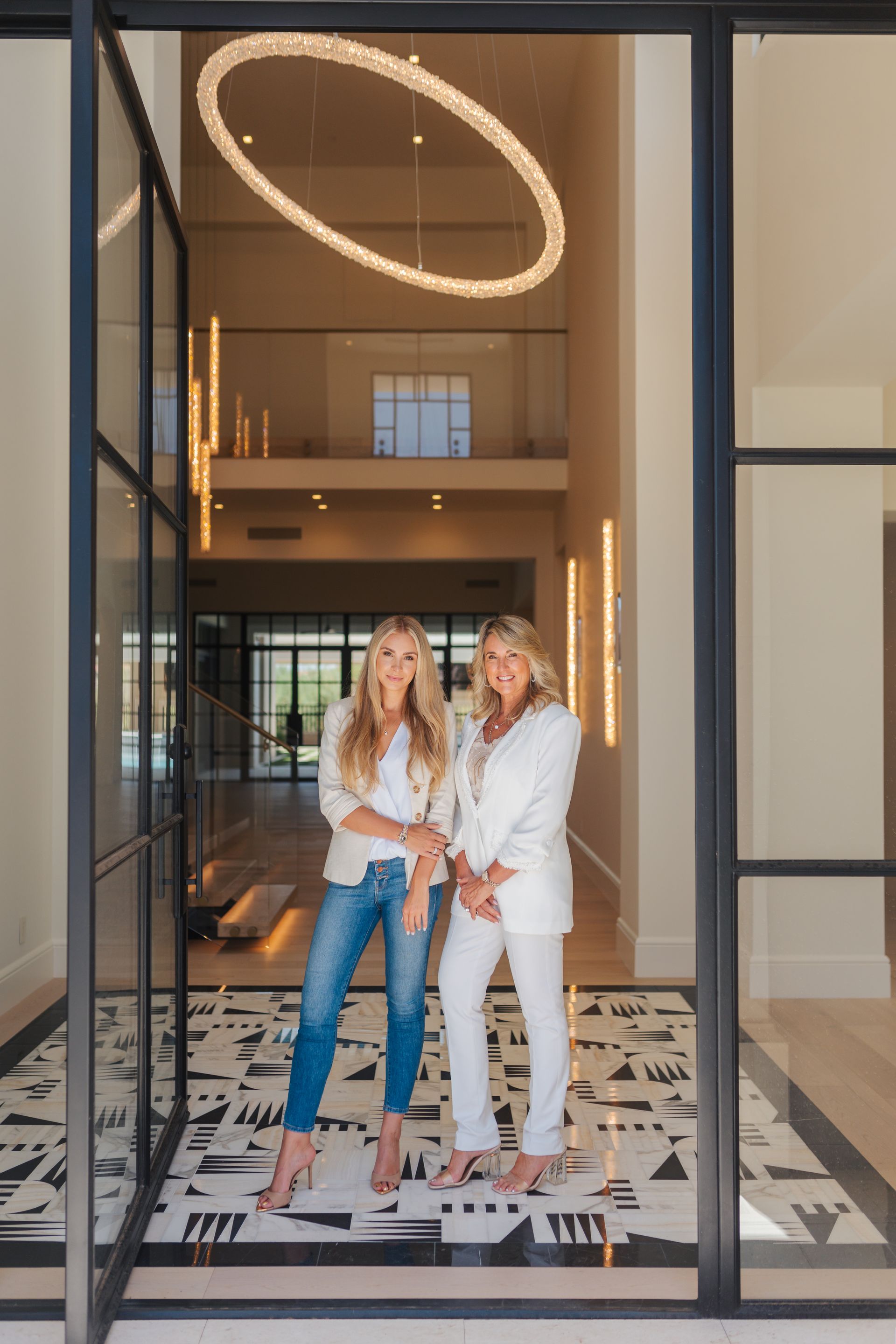 Two women are standing next to each other in front of a glass door.