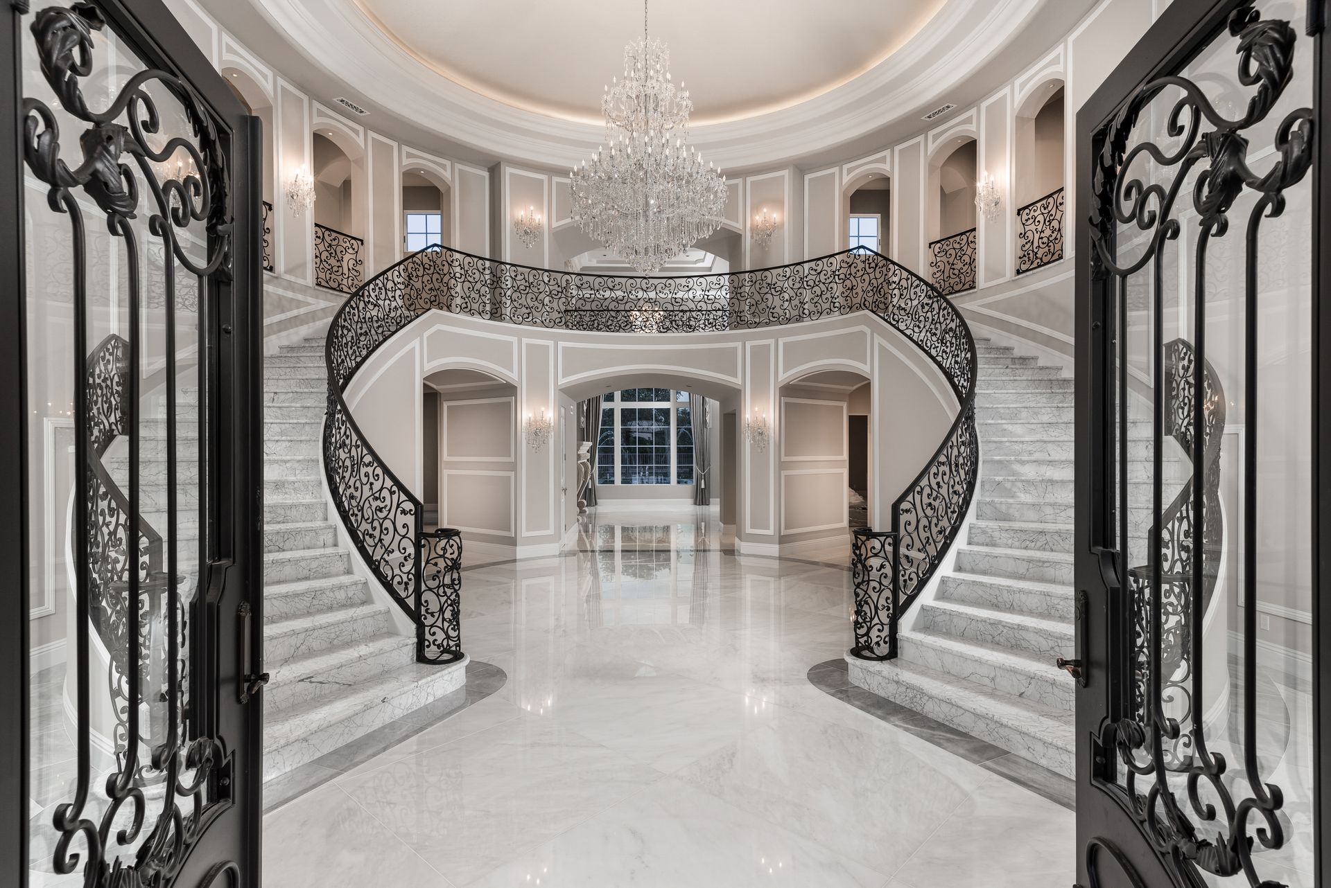 Luxury foyer with curved marble staircase and chandelier