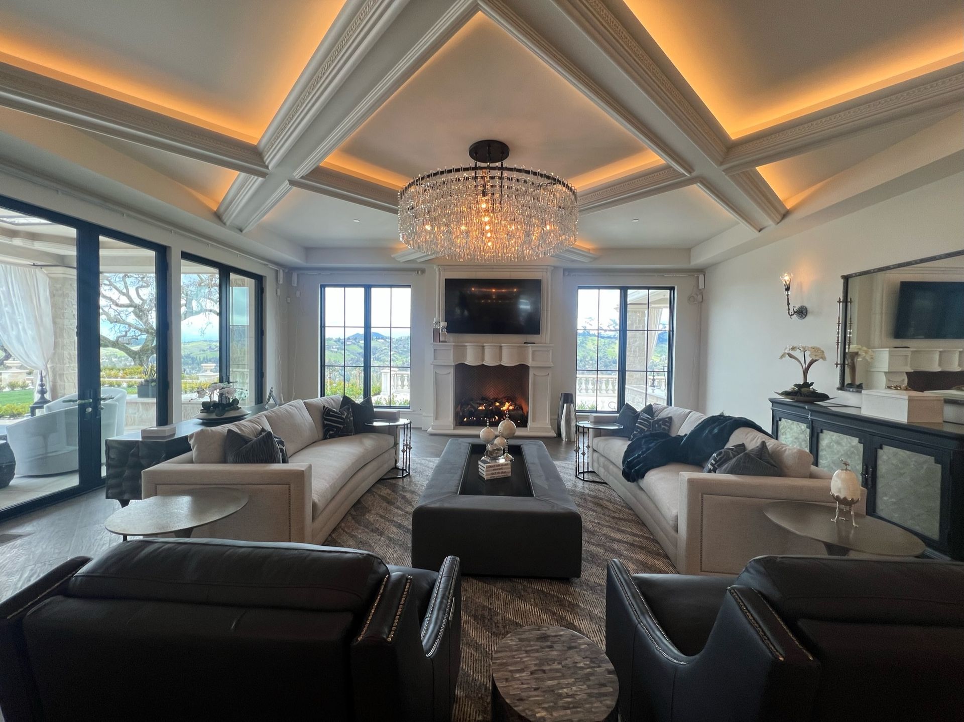 Transitional living room with vaulted ceiling, chandelier, fireplace, and large windows