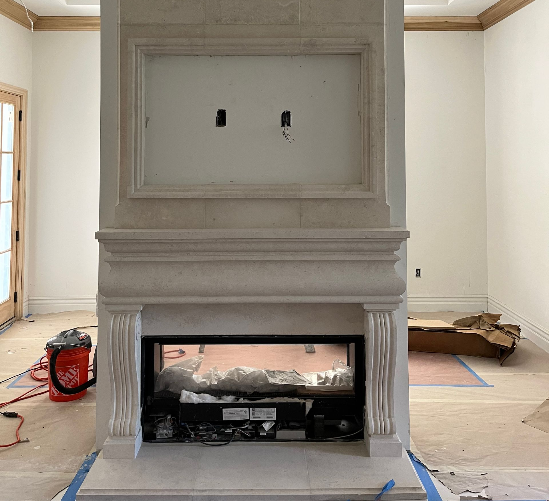 A partially constructed fireplace with a recessed area for a TV. The room is under construction.