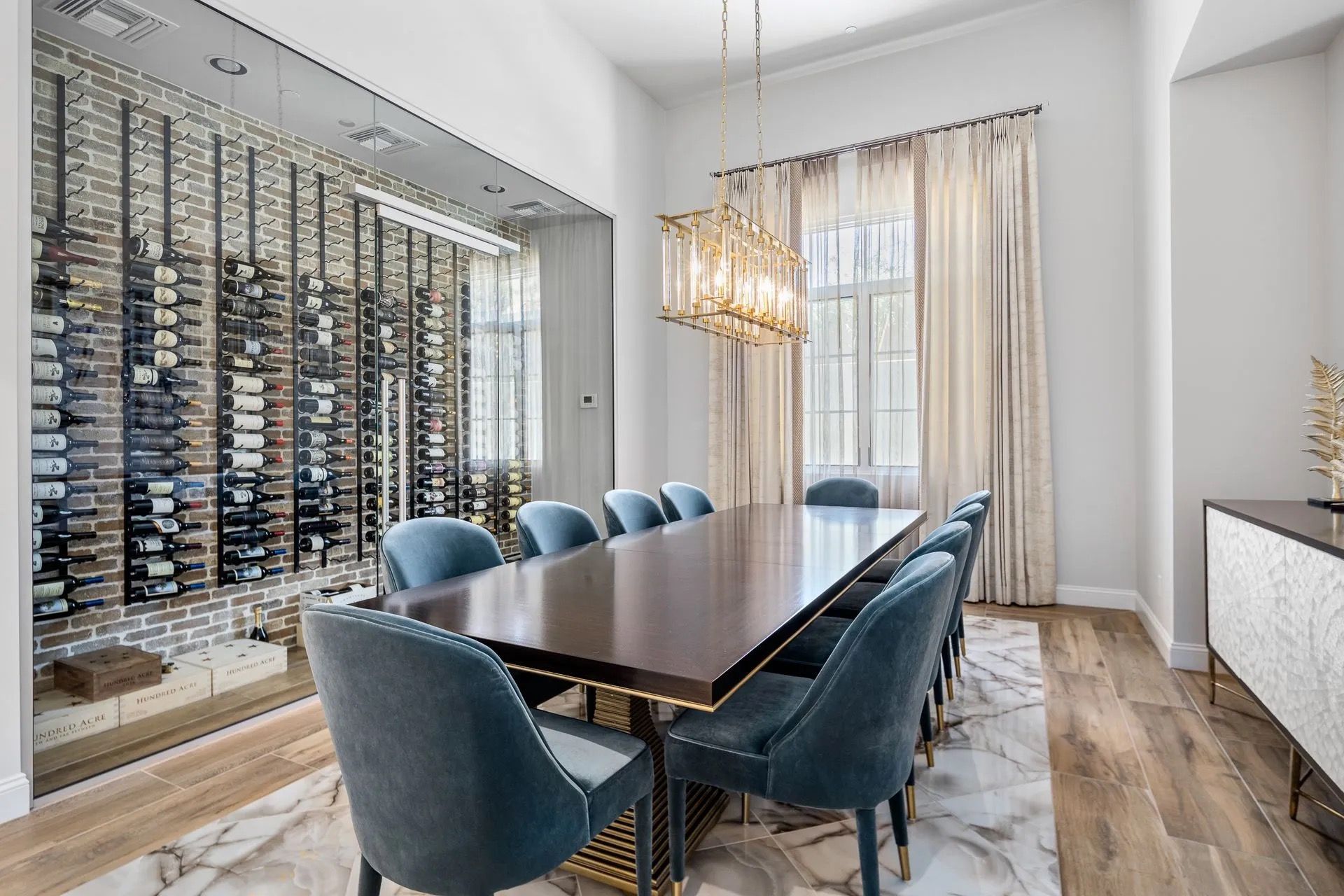 Elegant dining room with wine storage wall, long table, and blue chairs.