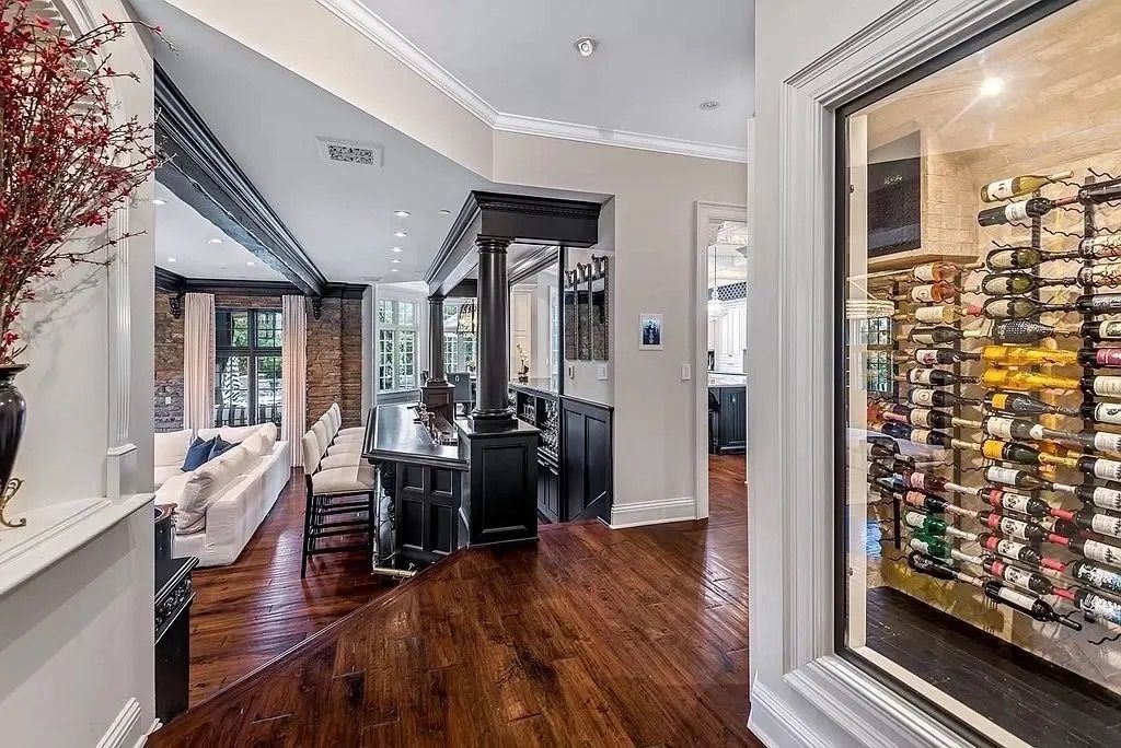 Hallway with wine cellar and entry to living room; dark wood floors, white trim, brick wall.