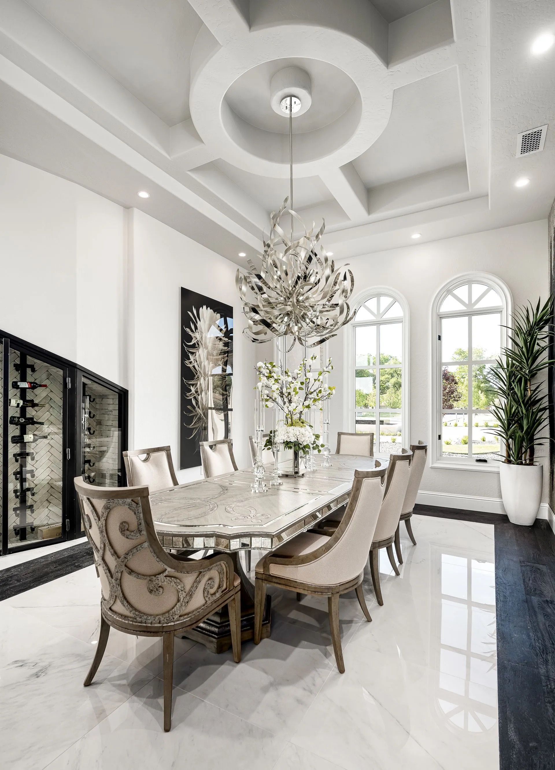 Elegant dining room with chandelier, long table, chairs, and wine storage.