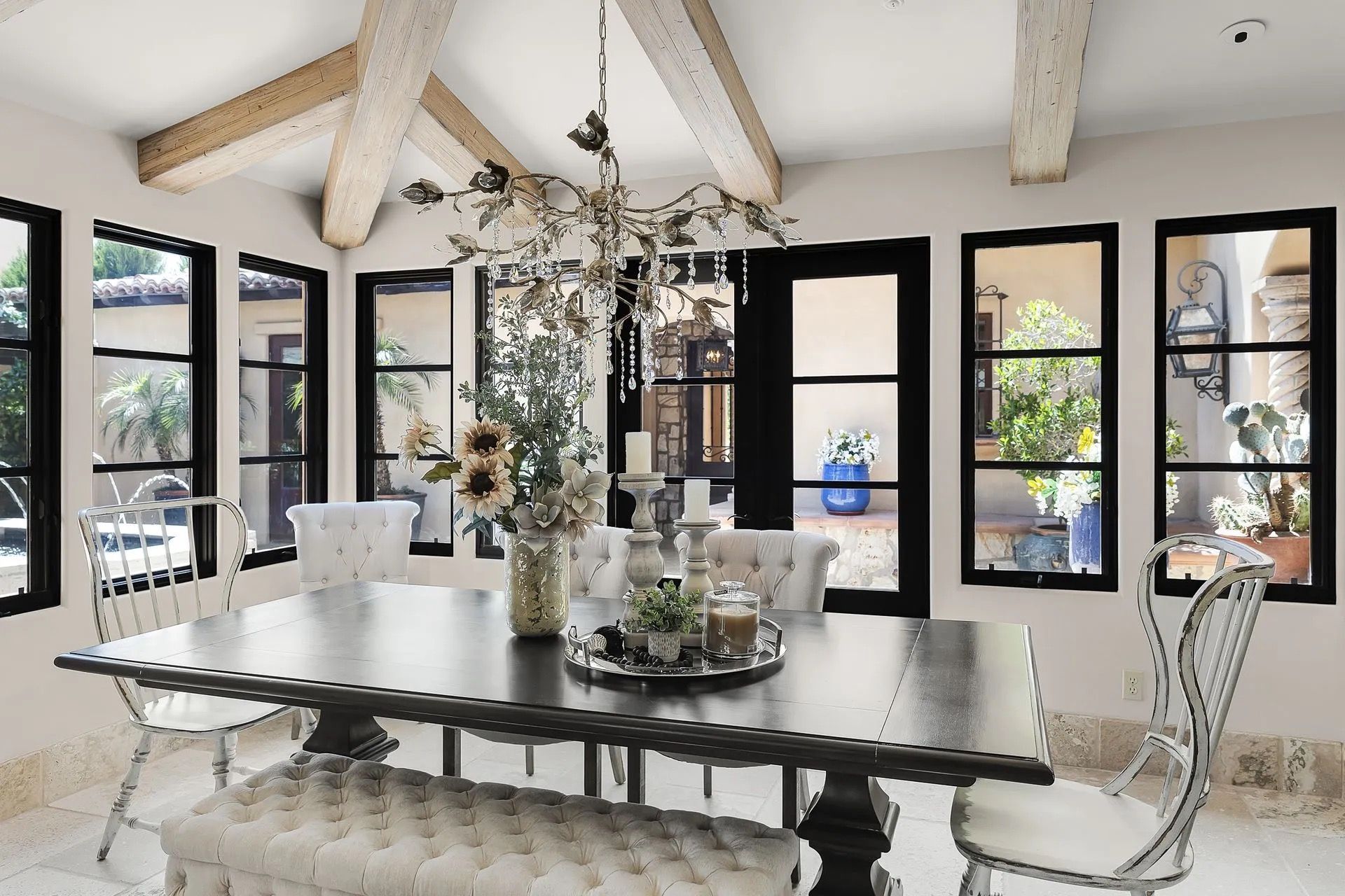 Dining room with a long table, white chairs, and large windows.