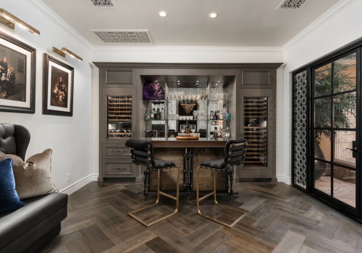 Home bar with wood accents, including wine storage, seating, and open glass door to outdoor area.