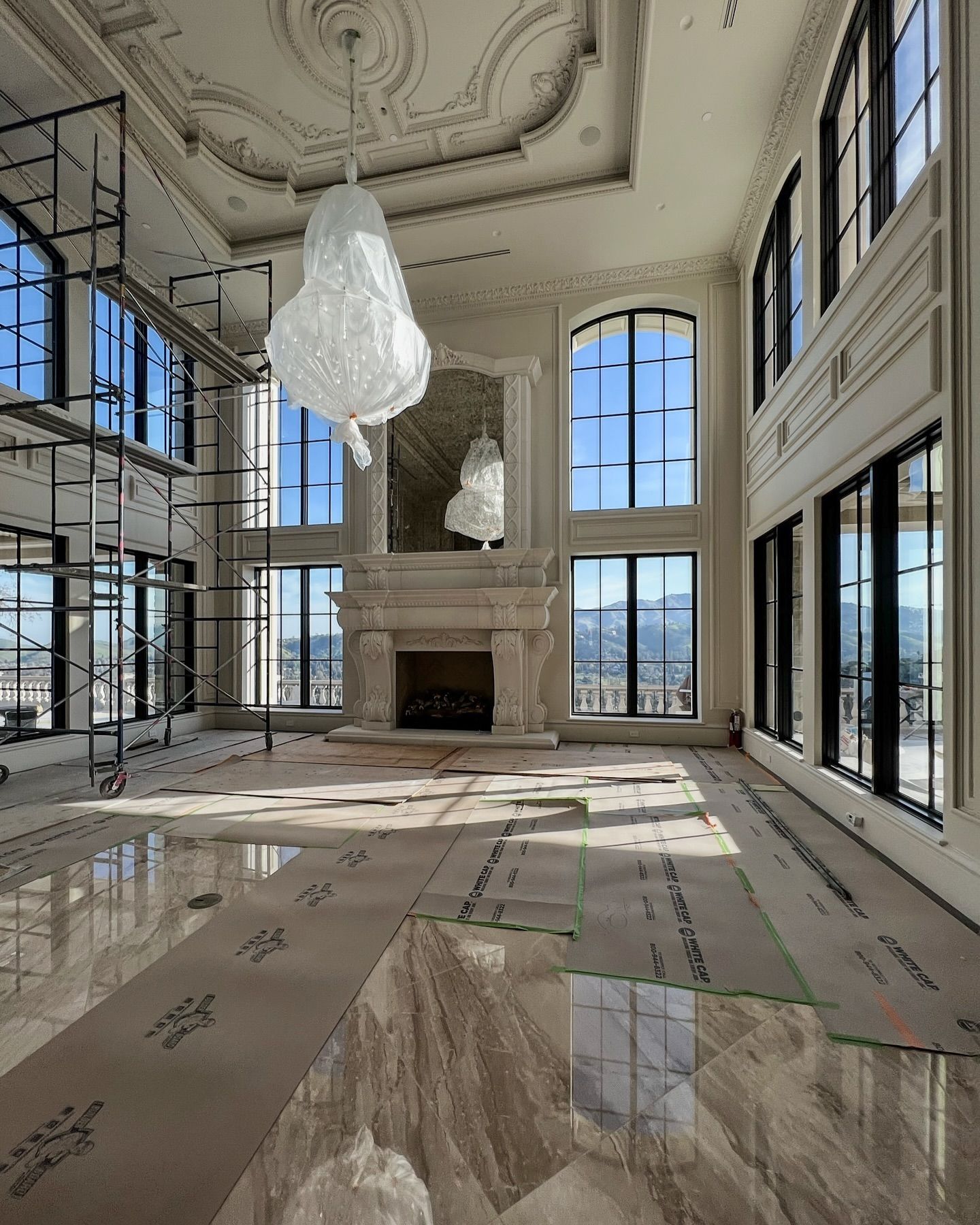Luxury old world living room with detailed millwork, dual height ceilings and arched windows