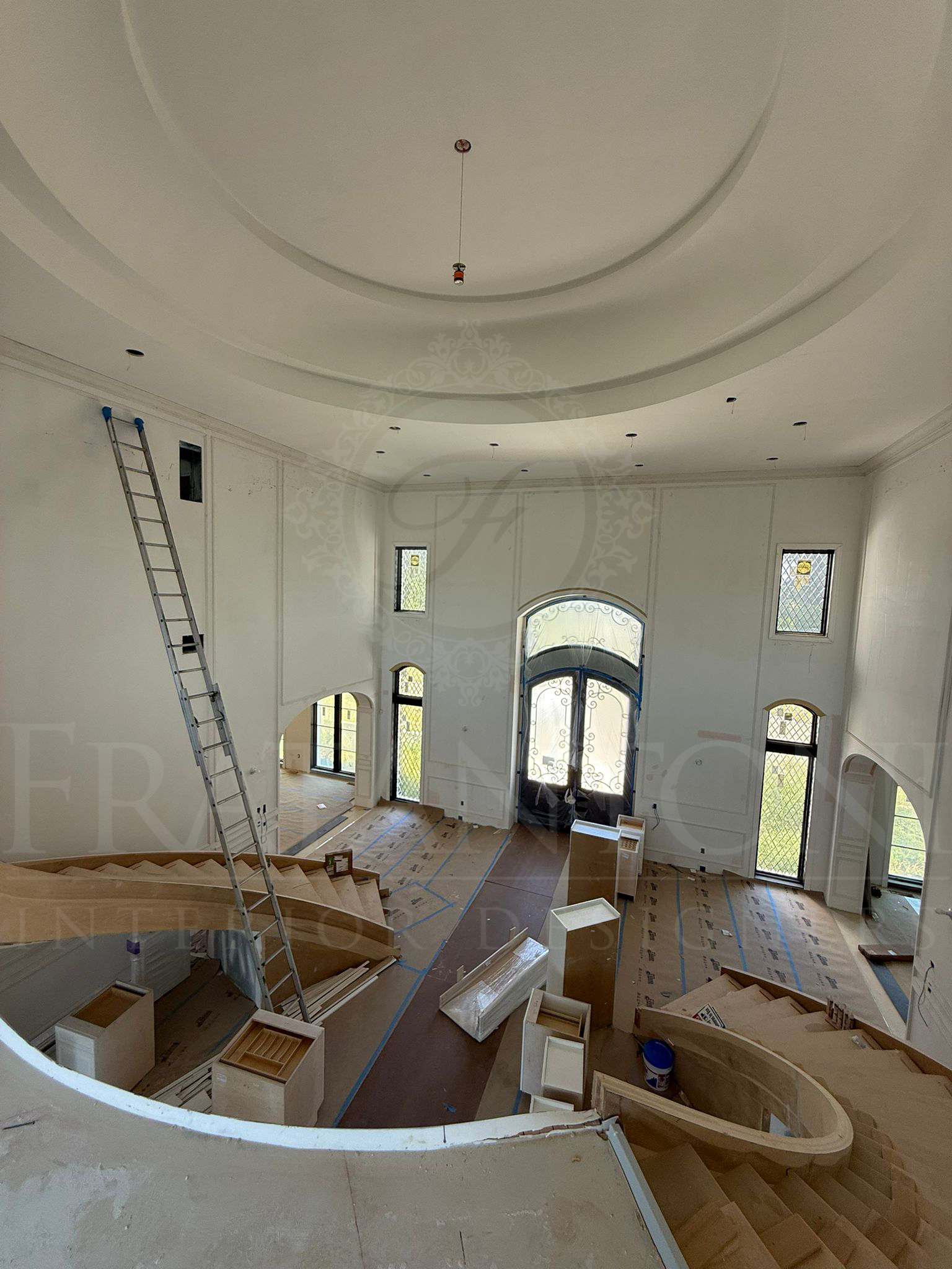 Spacious unfinished home interior with curved balcony, tall windows, arched door, wall panelling, and dramatic staircase in New Jersey