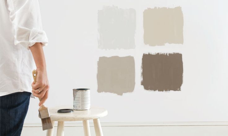 A woman is standing next to a stool holding a paint brush.