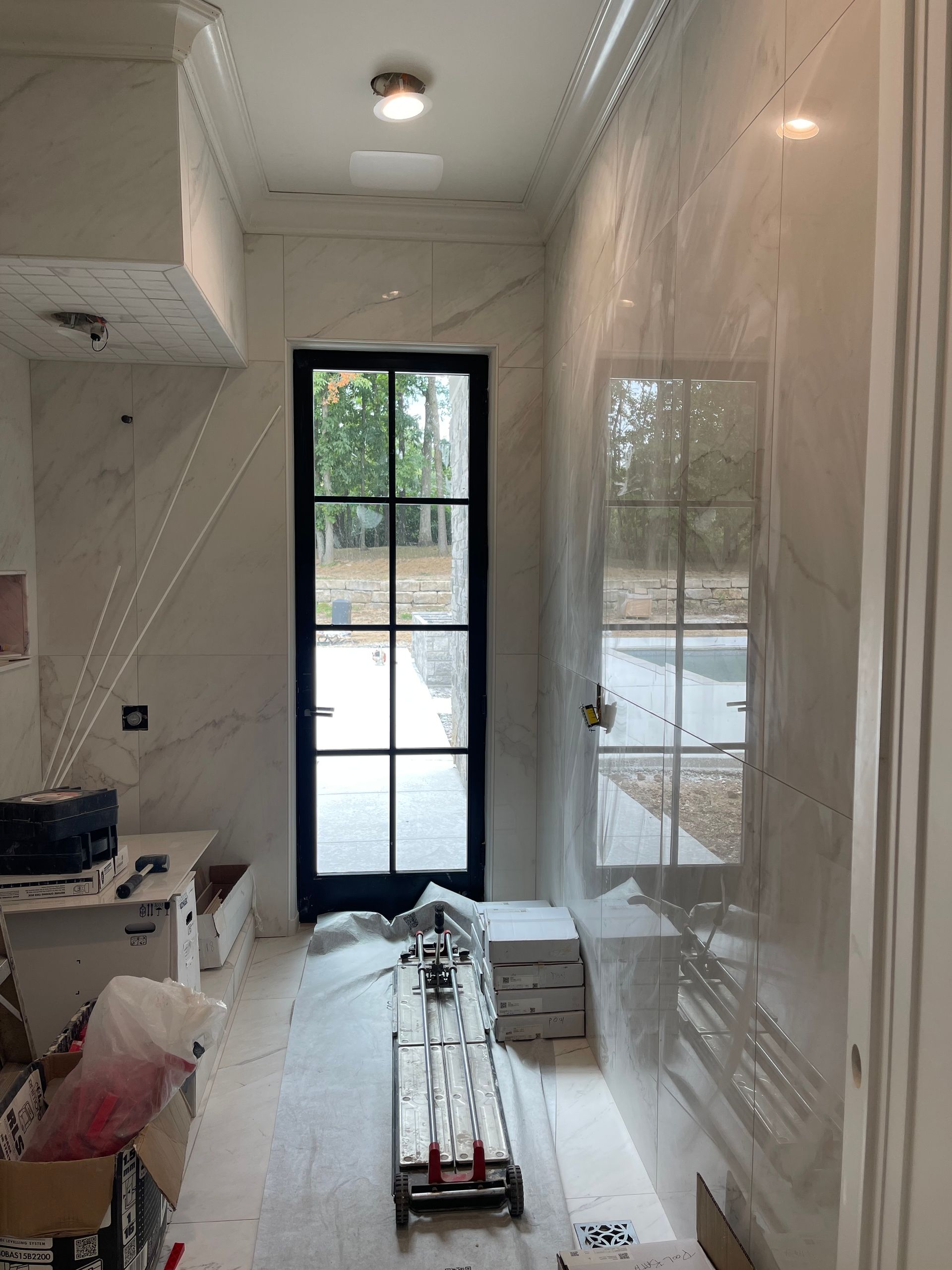 Bathroom with marble walls and a black framed door and window.