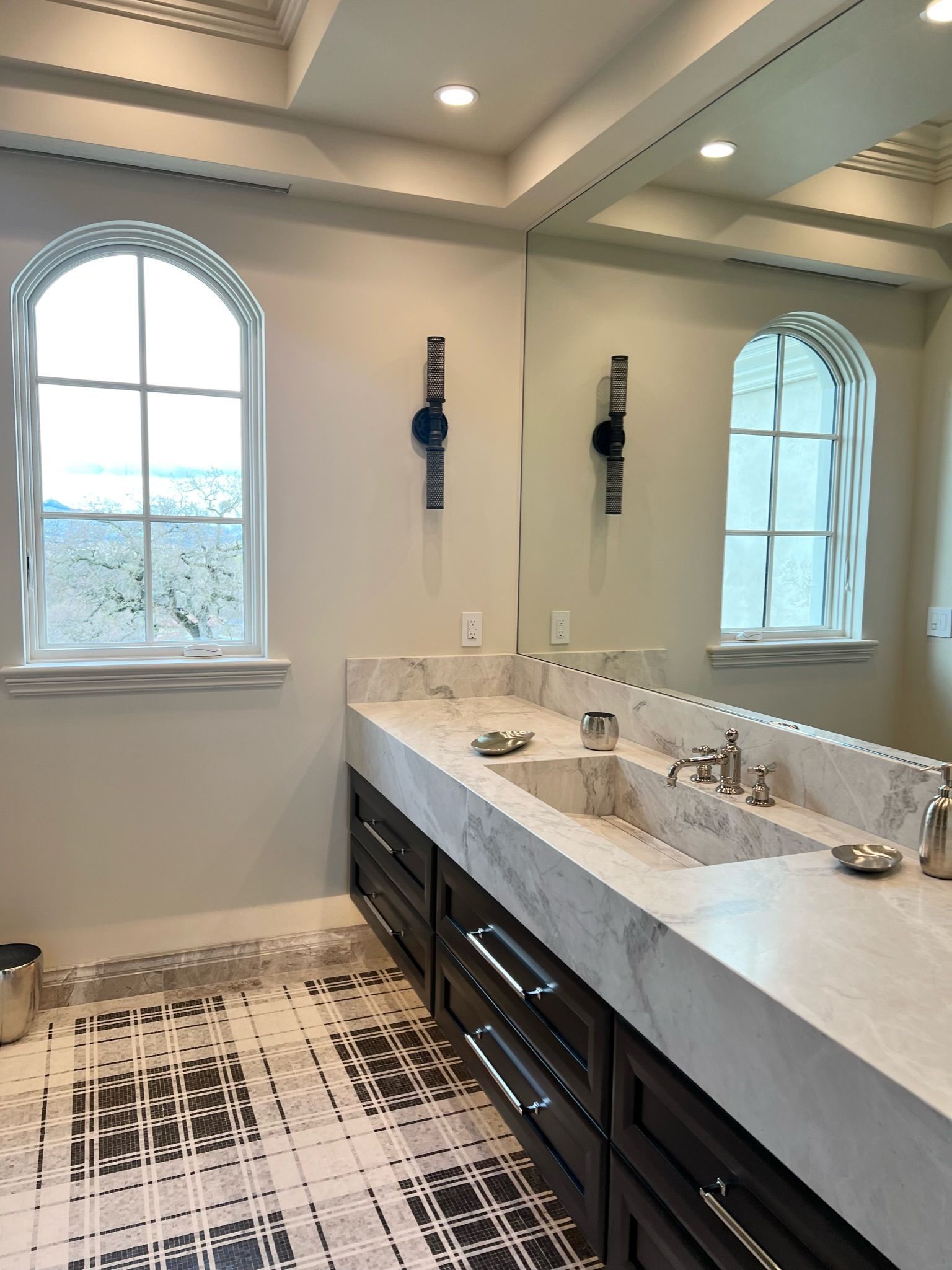 Bathroom with double sink vanity, arched windows, and checkered floor.