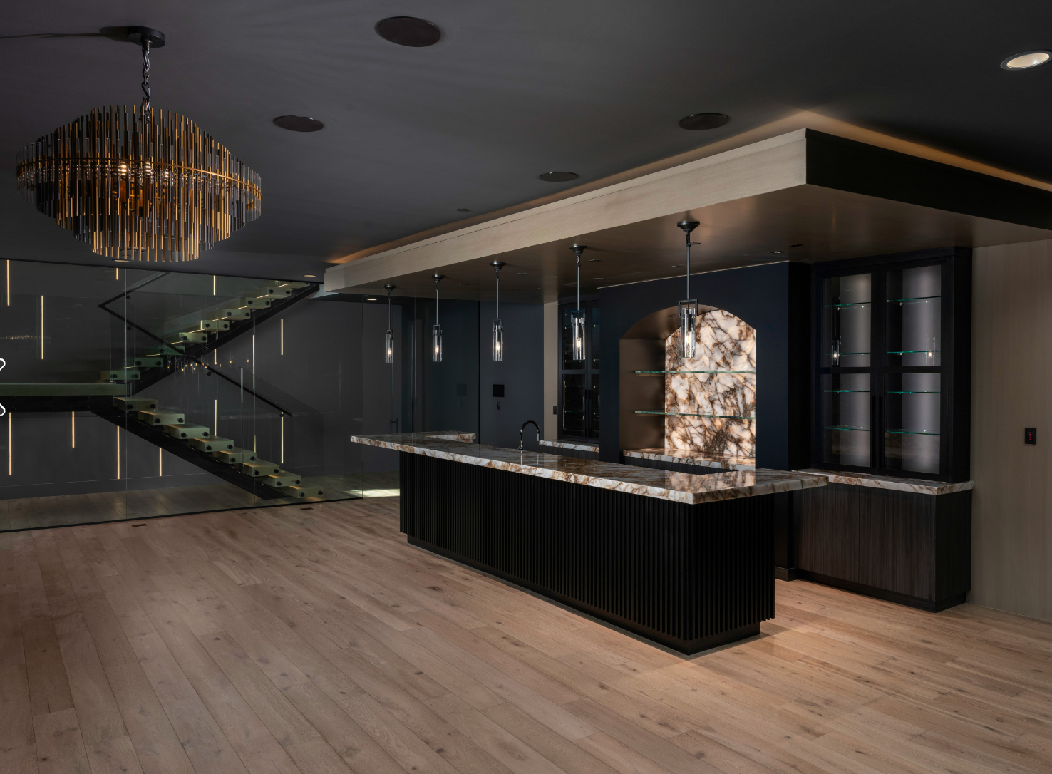 Luxurious basement bar with a dark color palette, wood floors, and a staircase.