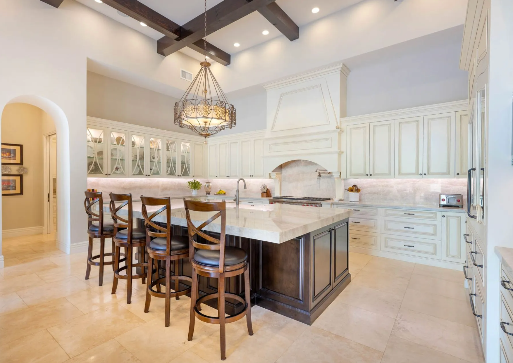 Spacious kitchen with island, seating, and ornate cabinetry in a neutral color palette.