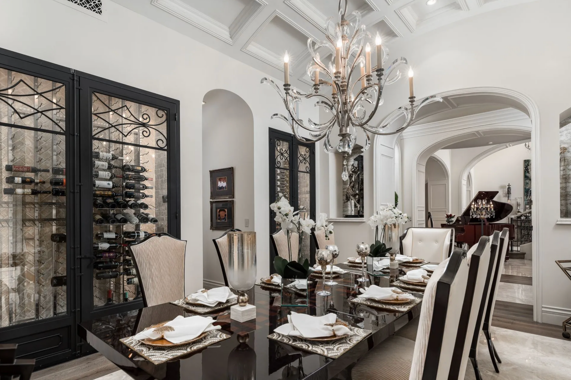 Elegant dining room with black table, chandelier, and a wine rack.
