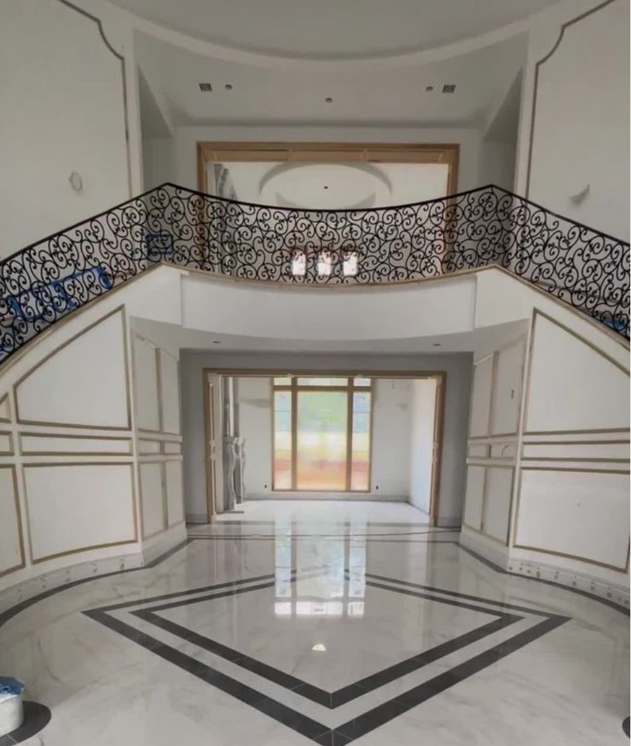 Grand foyer with marble floor, dual staircases, decorative railings, and large window.
