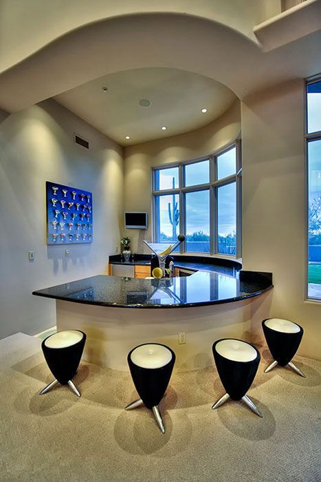 Kitchen with curved black granite countertop, four black and silver stools, and a large window.