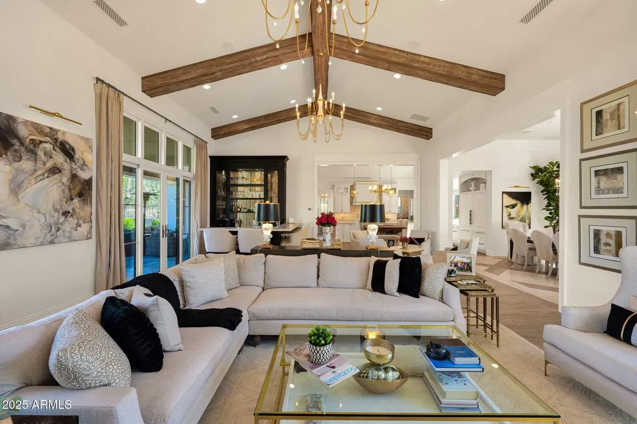 Spacious living room with a cream-colored sectional, wood beams, and a glass-top coffee table.